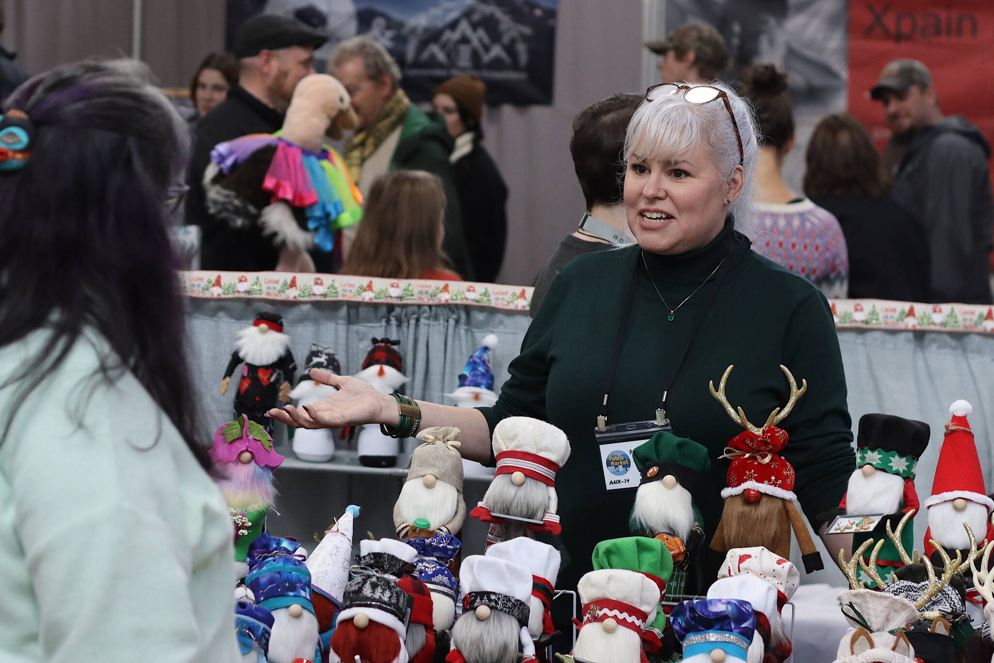 Tracy Eshelman, a former Juneau resident who attended her first Juneau Public Markets during their early years in the 1980s, describes her handmade holiday-theme gnomes to a shopper Saturday in the Juneau Arts Humanities Council building. She is a first-time vendor at the market, after creating the gnomes to lift people’s spirits during the COVID-19 pandemic. (Mark Sabbatini / Juneau Empire)