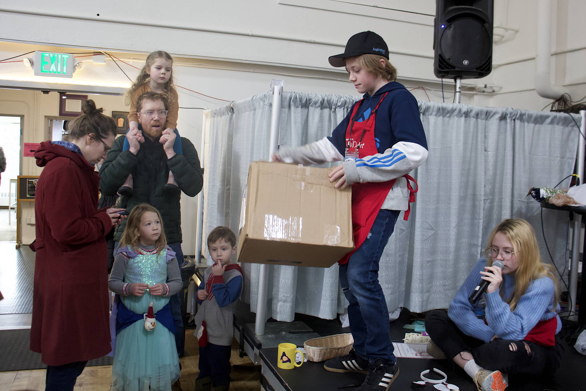 Angus Andrews, 13, pulls a ticket slip from a box during a prize drawing at the Juneau Public Market on Saturday. He said he has been working at the market since the age of 5 when he helped Santa distribute presents. (Mark Sabbatini / Juneau Empire)