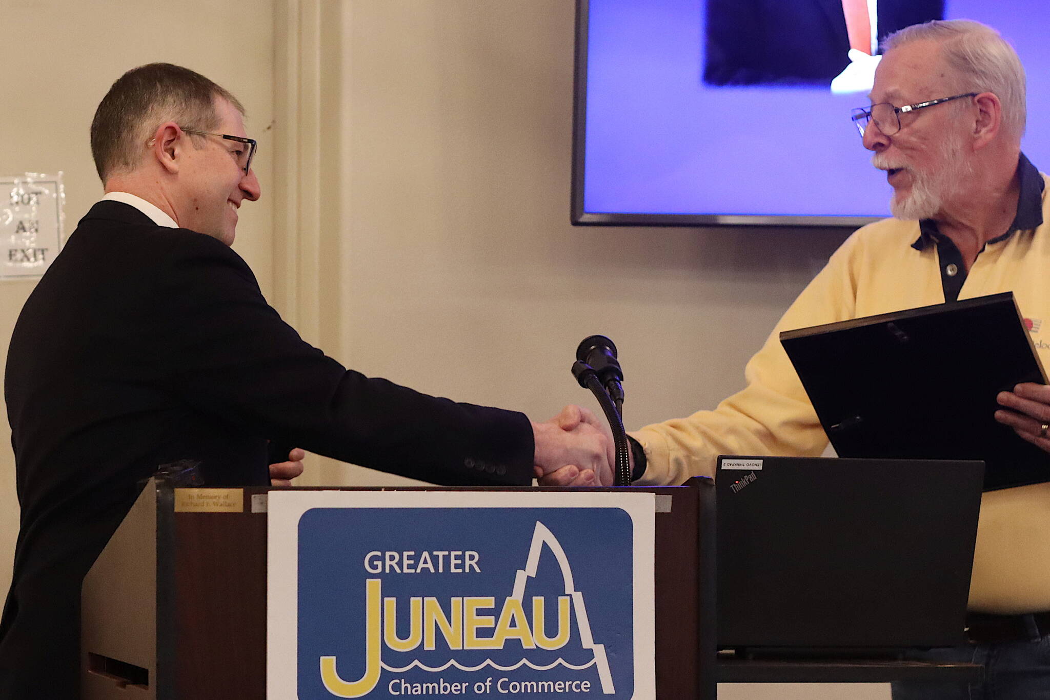 Juneau State Sen. Jesse Kiehl, left, gives a legislative proclamation to former longtime Juneau Assembly member Loren Jones, who stepped down last year due to term limits, following Kiehl’s speech at the Juneau Chamber of Commerce’s weekly luncheon Thursday at the Juneau Moose Family Center. (Mark Sabbatini / Juneau Empire)