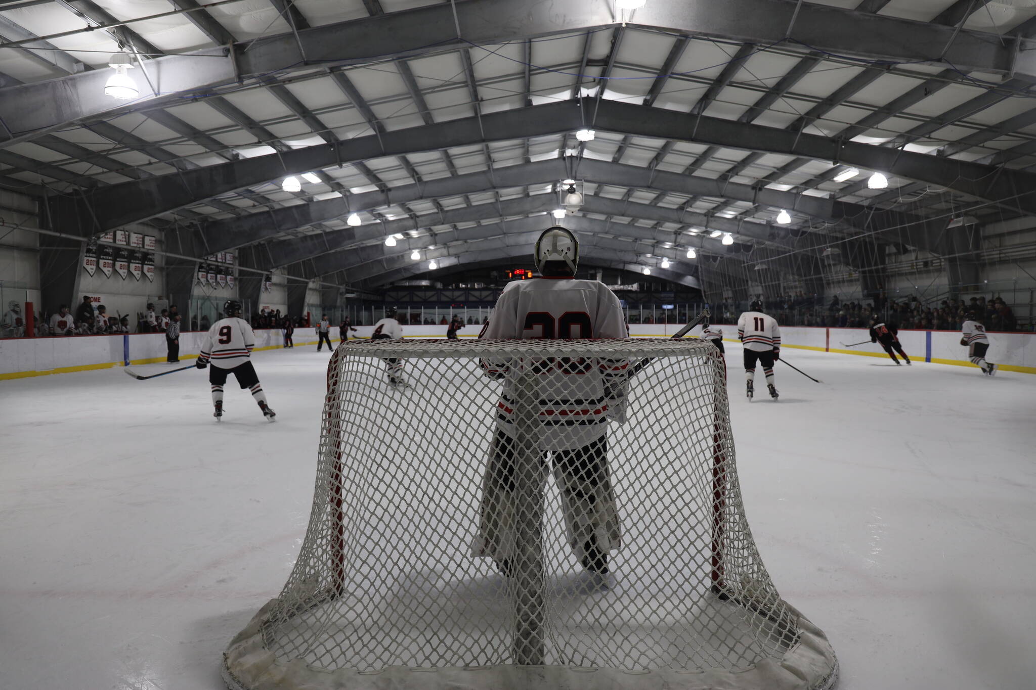Junior Mason Sooter tends the net as the puck moves to the opposite zone during a home game between Juneau-Douglas High School: Yadaa.at Kalé Crimson Bears Varsity hockey team and the Kenai Central Kardinals at the Treadwell Arena Saturday afternoon. (Clarise Larson / Juneau Empire)
