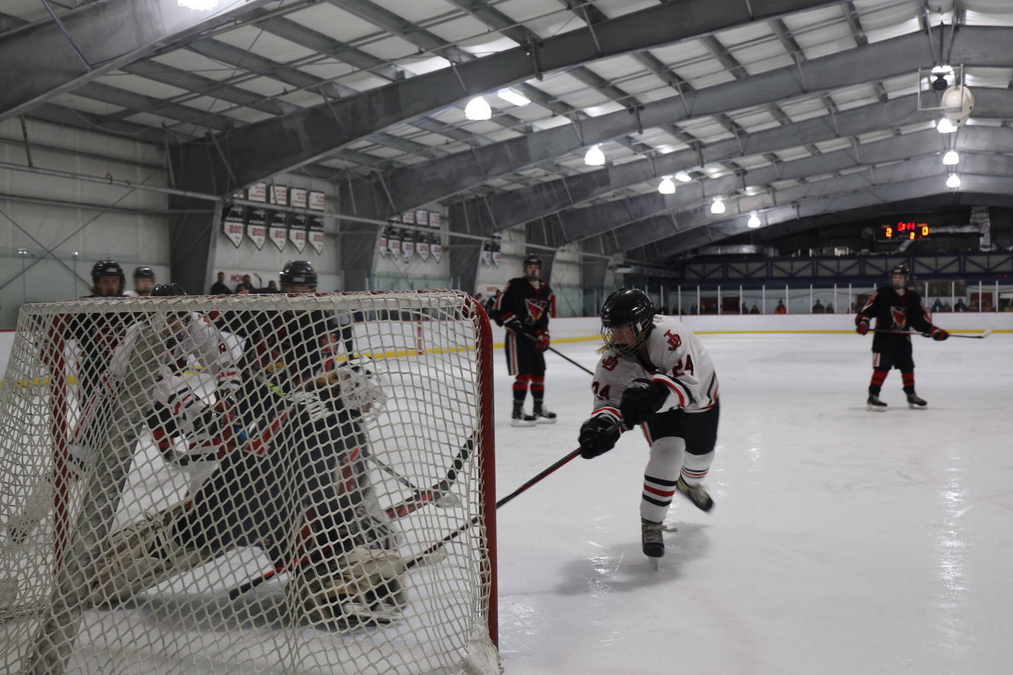 Senior Anna Dale attempts to stuff the net during a home game between Juneau-Douglas High School: Yadaa.at Kalé Crimson Bears Varsity hockey team and the Kenai Central Kardinals at the Treadwell Arena Saturday afternoon. (Clarise Larson / Juneau Empire)