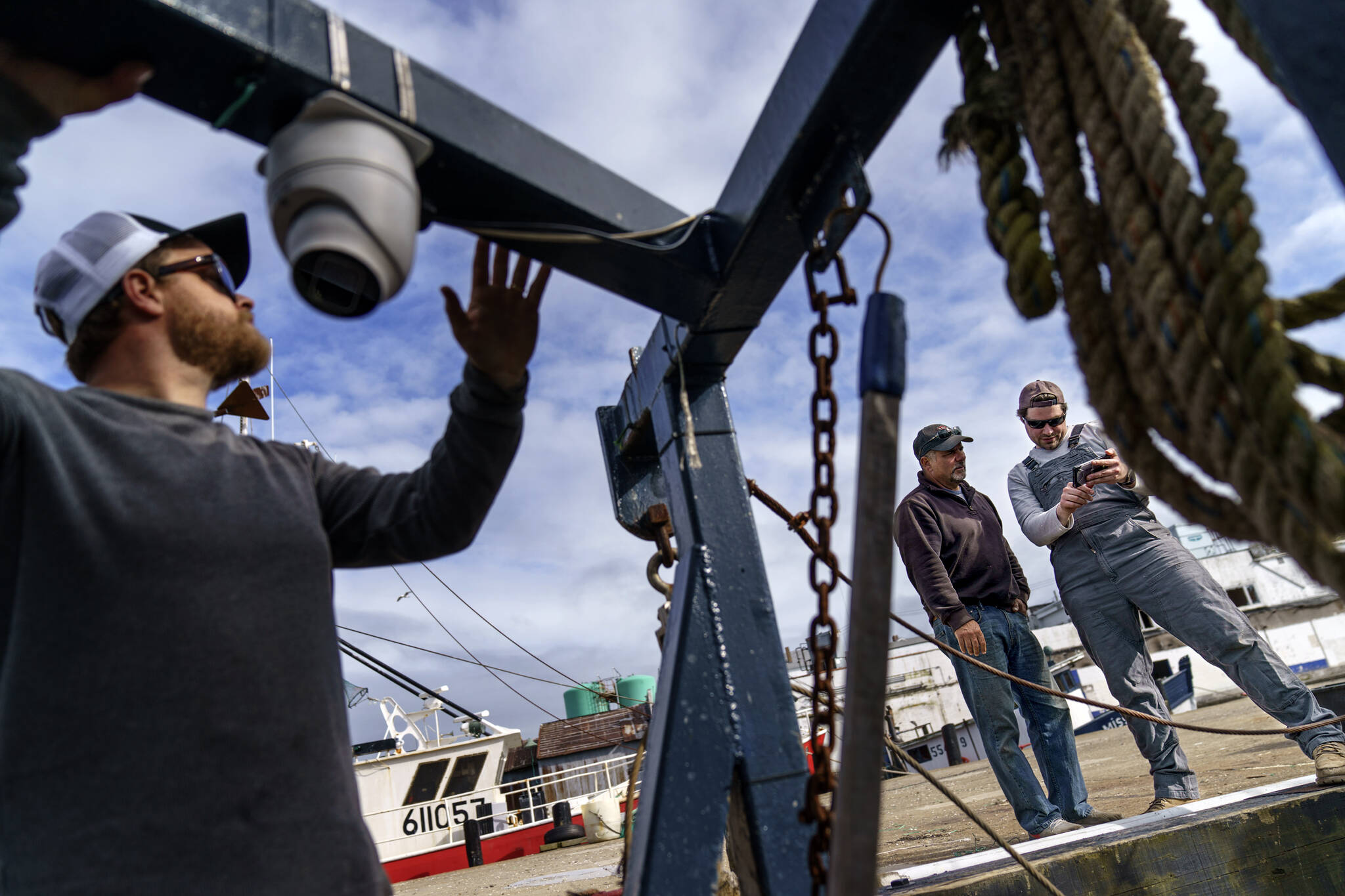 Mark Hager, left, positions a camera with the help of Anthony Lucia, right, as captain Al Cottone watches the feed on a monitor from his boat, the Sabrina Maria, in Gloucester, Mass., May 11, 2022. Hager’s Maine-based startup, New England Maritime Monitoring, is one of a bevy of companies seeking to help commercial vessels comply with new federal mandates aimed at protecting dwindling fish stocks. But taking the technology overseas, where the vast majority of seafood consumed in the U.S. is caught, is a steep challenge. (AP Photo / David Goldman)