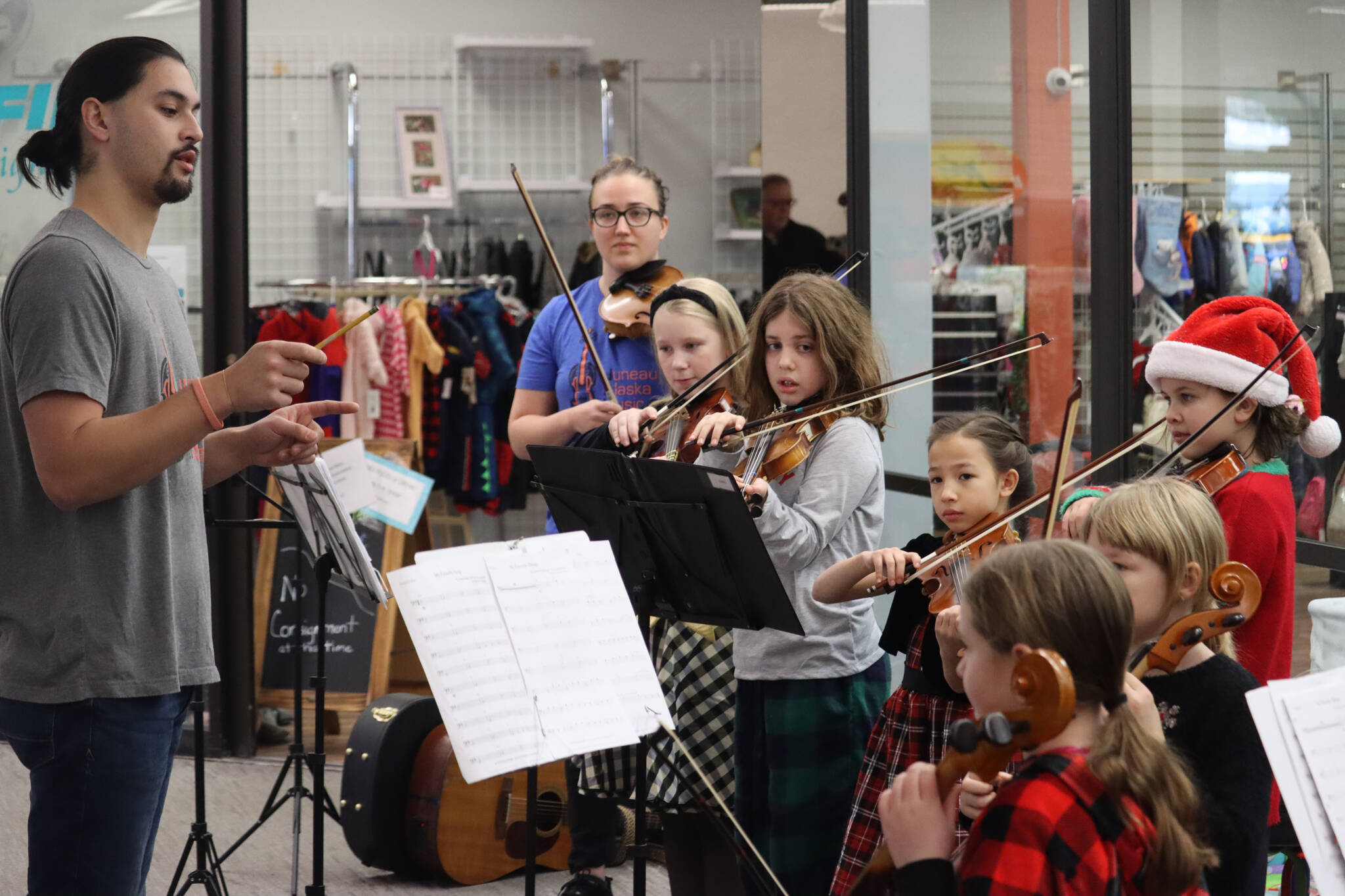 Instructor James Cheng with Juneau Alaska Music Matters conducts students from the intermediate program on Saturday during the annual Holiday Village event at the Mendenhall Mall. (Jonson Kuhn / Juneau Empire)