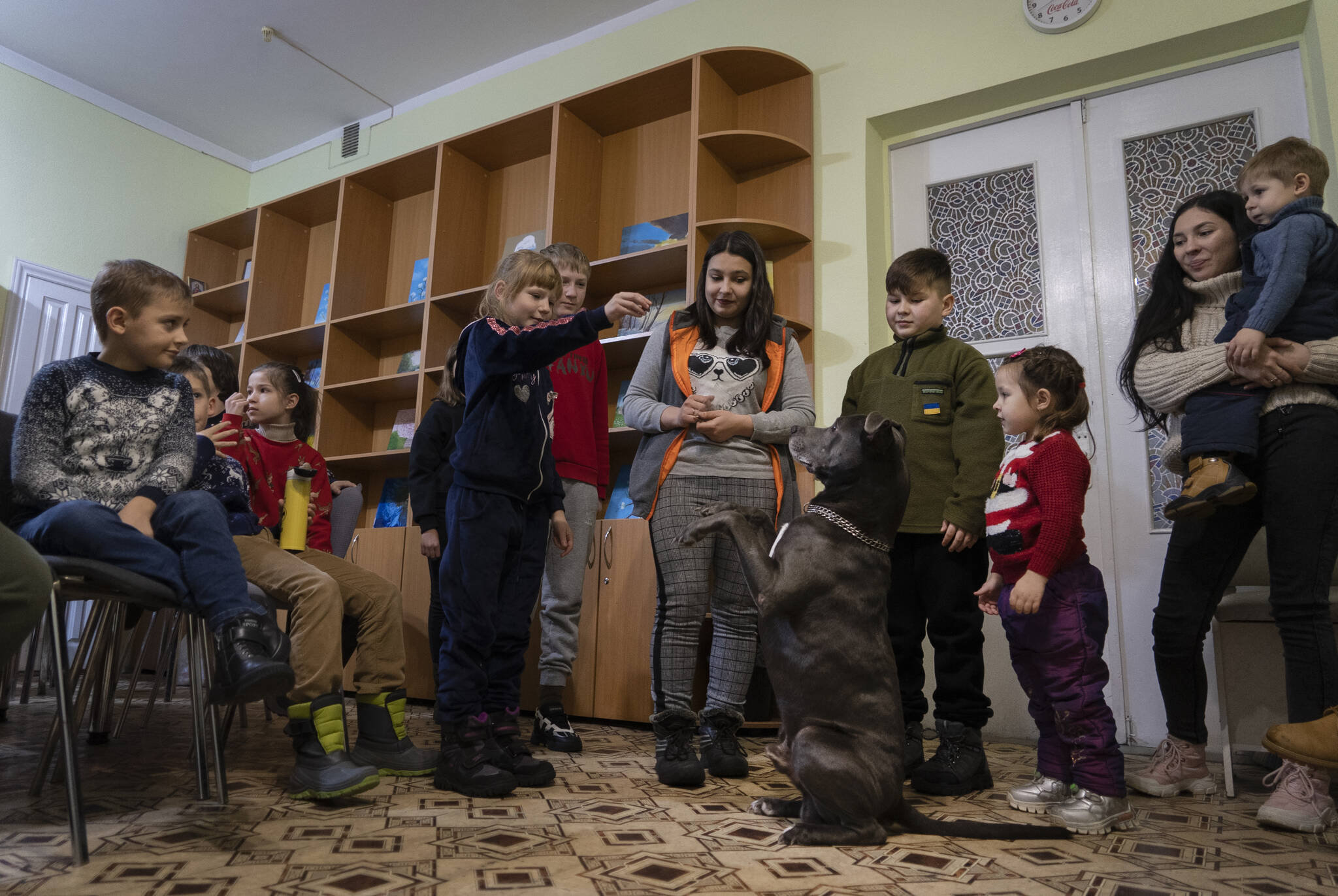 Children traumatized by the war play with an American Pit Bull Terrier “Bice” in the Center for Social and Psychological Rehabilitation in Boyarka close Kyiv, Ukraine, Wednesday, Dec. 7, 2022. Bice is an American pit bull terrier with an important and sensitive job in Ukraine — comforting children traumatized by the war. The Center for Social and Psychological Rehabilitation is a state-operated community center where a group of people are trying to help those who have experienced a trauma after the Feb. 24 Russian invasion, and now they are using dogs like Bice to give comfort. (AP Photo / Vasilisa Stepanenko)