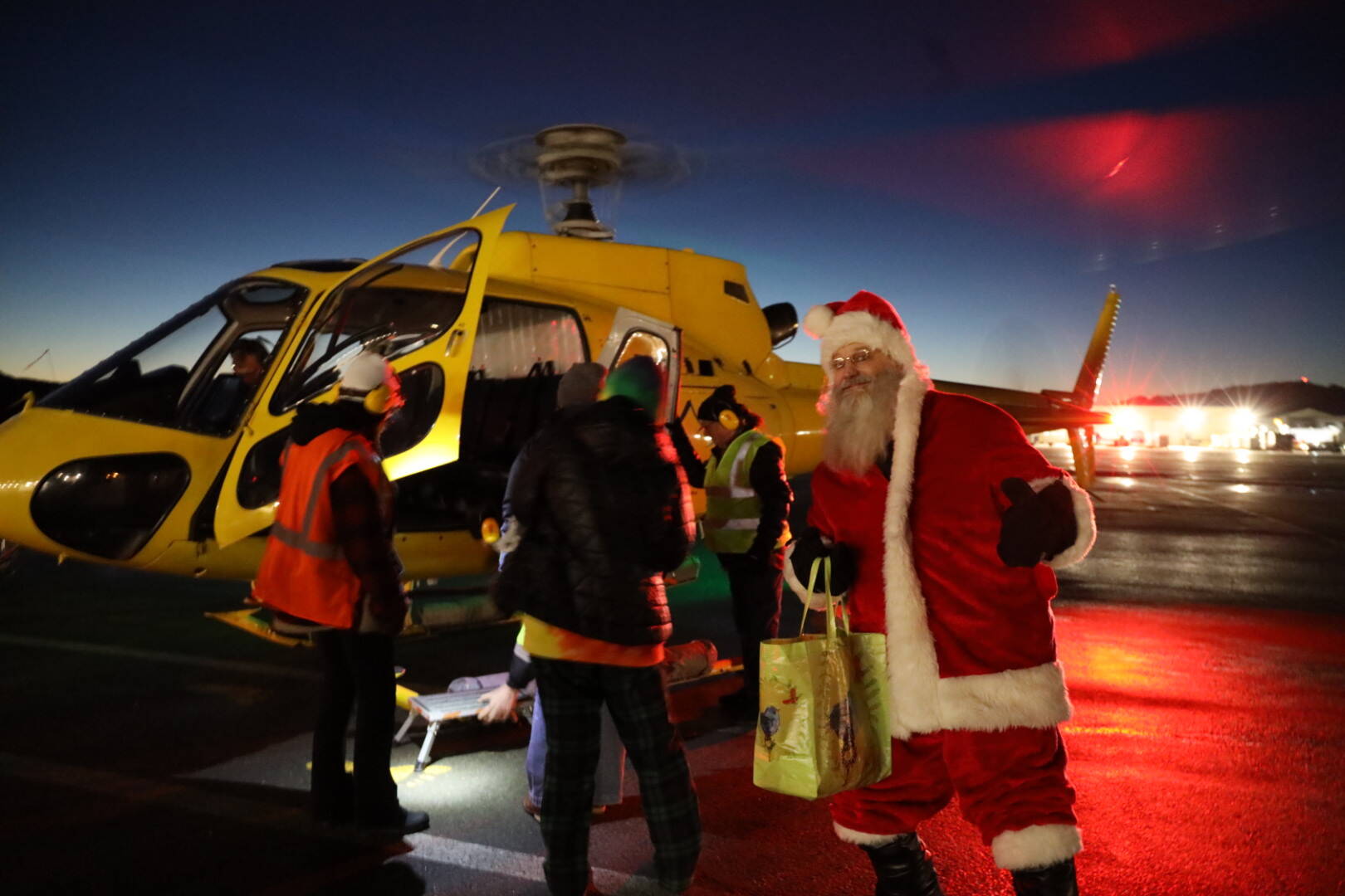 Santa steps off of a helicopter at Juneau International Airport for Christmas Light Flights. This year marked a triumphant return for the event which offers people an aerial view of Juneau during the holiday season. Flying time and staffing are donated by Coastal Helicopters and fuel from Petro Marine Services for the event. (Clarise Larson / Juneau Empire)