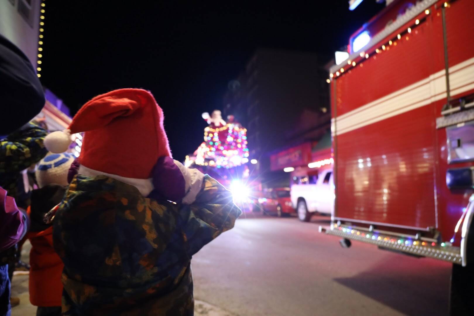 Callan Wilburn, 4, covers his ears with his mittens as the Capital City Fire/Rescue vehicles drive downtown for the Santa parade Saturday evening. (Clarise Larson / Juneau Empire)