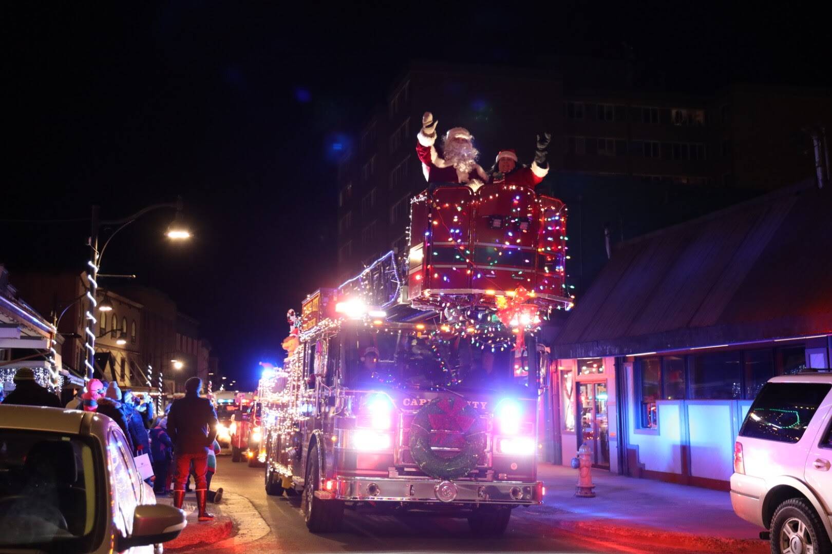 Mr and Mrs. Claus wave to residents from above as they sit in in the basket of a Capital City Fire/Rescue ladder truck for the Santa parade Saturday evening. (Clarise Larson / Juneau Empire)