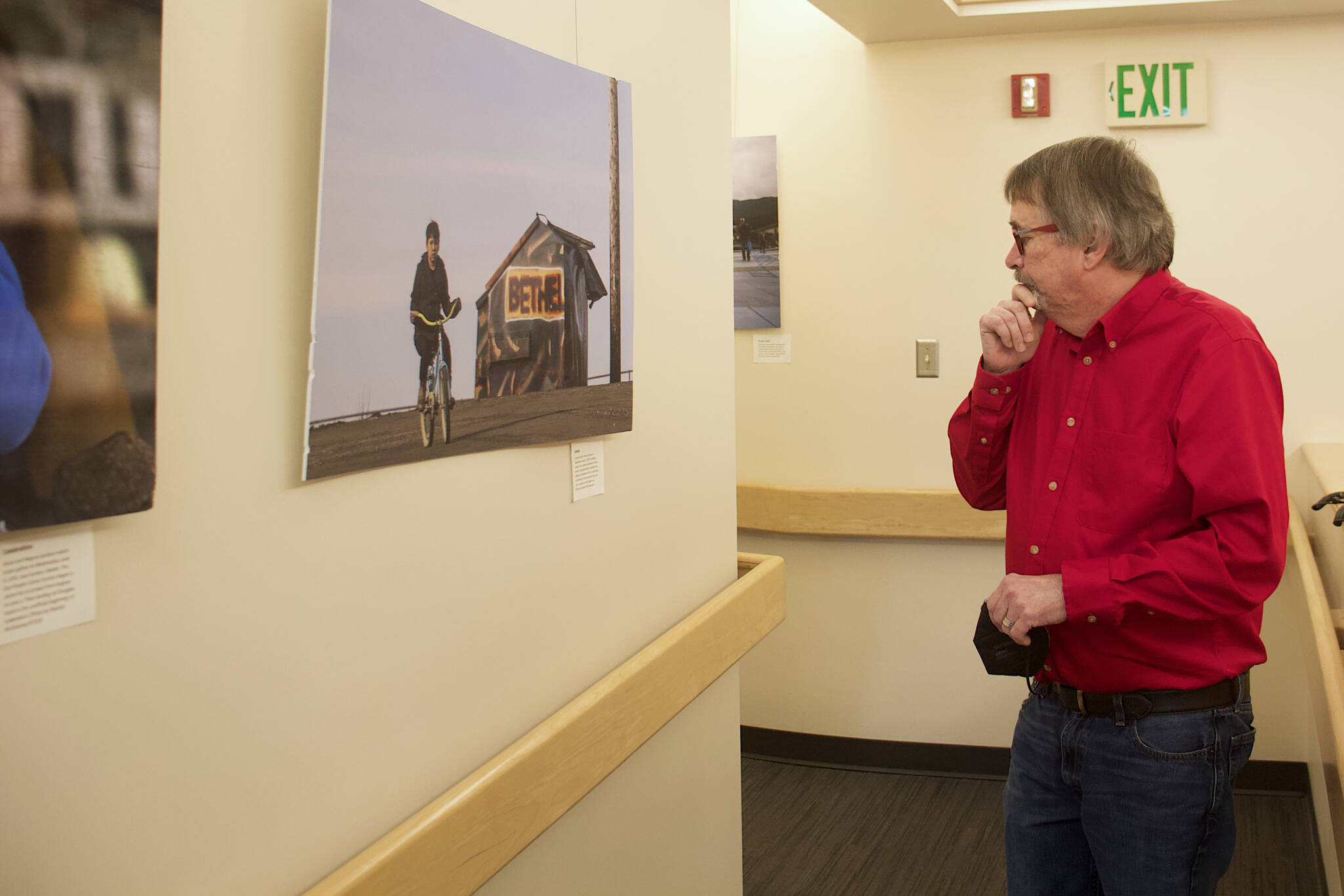 Bill Legere, president and general manager of KTOO, examines pictures from around the state by a former photographer in a hallway he selected as favorites to display in a hallway at the station. (Mark Sabbatini / Juneau Empire)