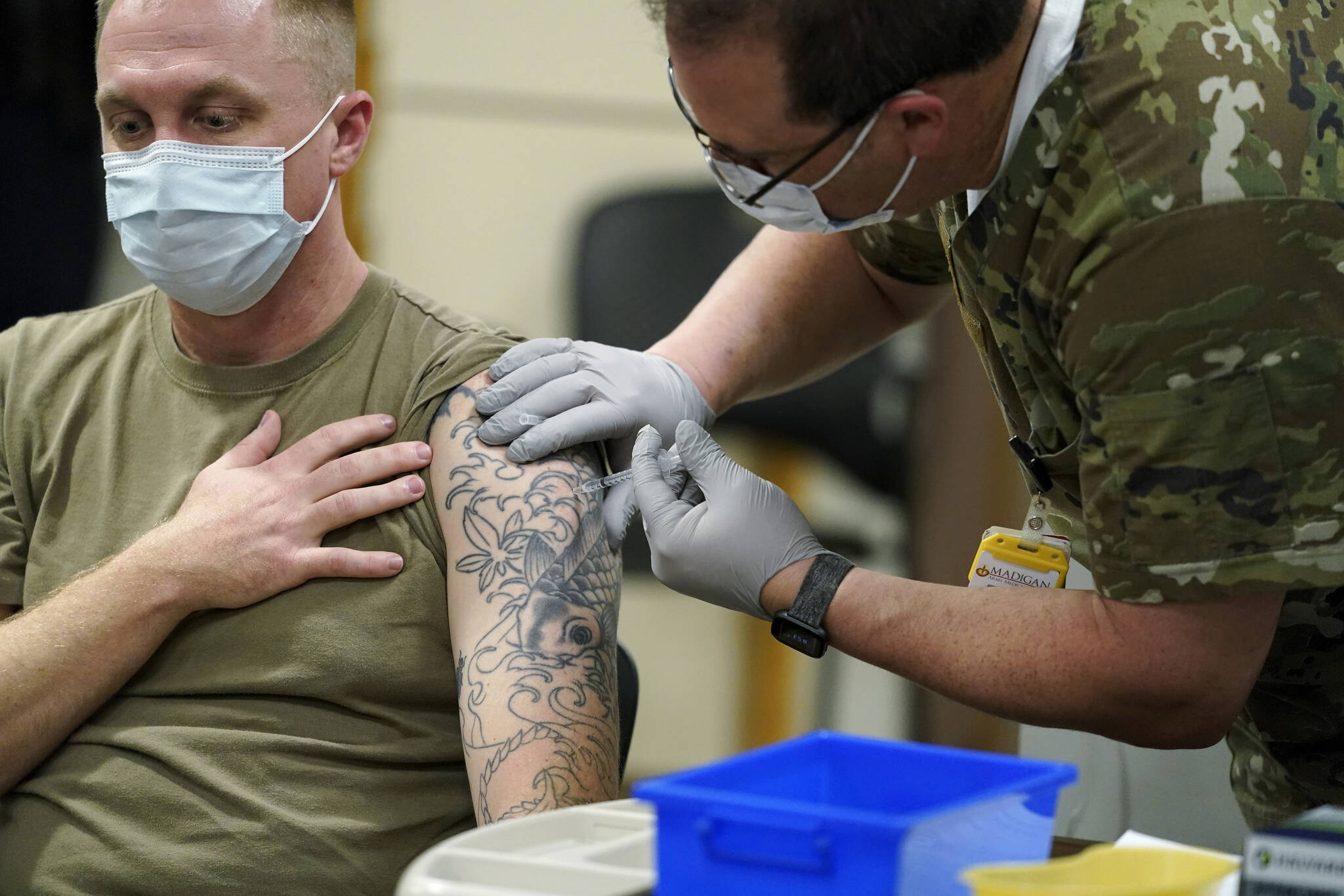 Staff Sgt. Travis Snyder, left, receives the first dose of the Pfizer COVID-19 vaccine given at Madigan Army Medical Center at Joint Base Lewis-McChord in Washington state, Dec. 16, 2020, south of Seattle. U.S. military forces around the world will no longer be required to get the COVID-19 vaccine. The mandate was lifted under an $858 billion defense spending bill passed by Congress and signed into law Friday by President Joe Biden. (AP Photo / Ted S. Warren)