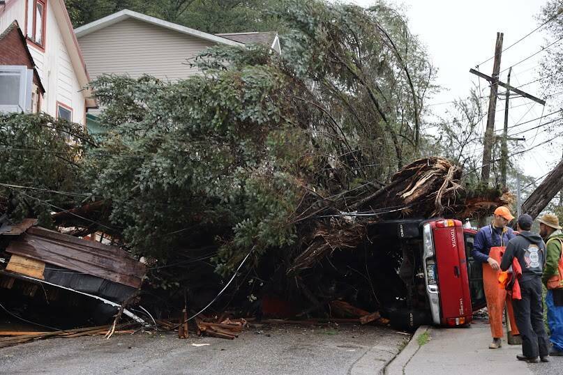 A tree and landslide debris lie across Gastineau Avenue after falling between two homes and crushing a vehicle on Gastineau Avenue during a heavy rainstorm Sept. 27. (Clarise Larson/The Juneau Empire)