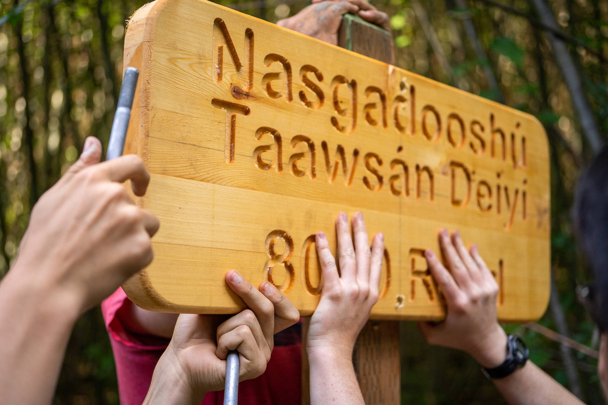 photos by Lee House / Sitka Conservation Society 
Many hands help to get the work done. Participants of the Alaska Youth Stewards program in Kake install a Lingít/English road sign, a project in partnership with community elders and the U.S. Forest Service.