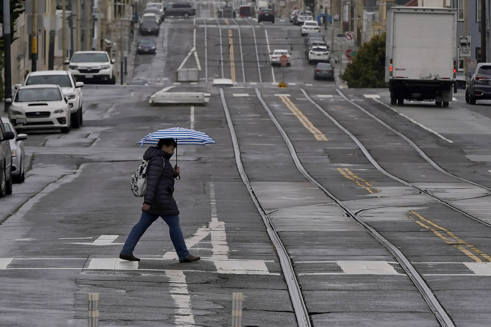 A pedestrian carries an umbrella while crossing a street in San Francisco, Thursday, April 14, 2022. A variety of new laws take effect Sunday, Jan. 1, 2023 that could have an impact on people’s finances and, in some cases, their personal liberties. (AP Photo / Jeff Chiu)