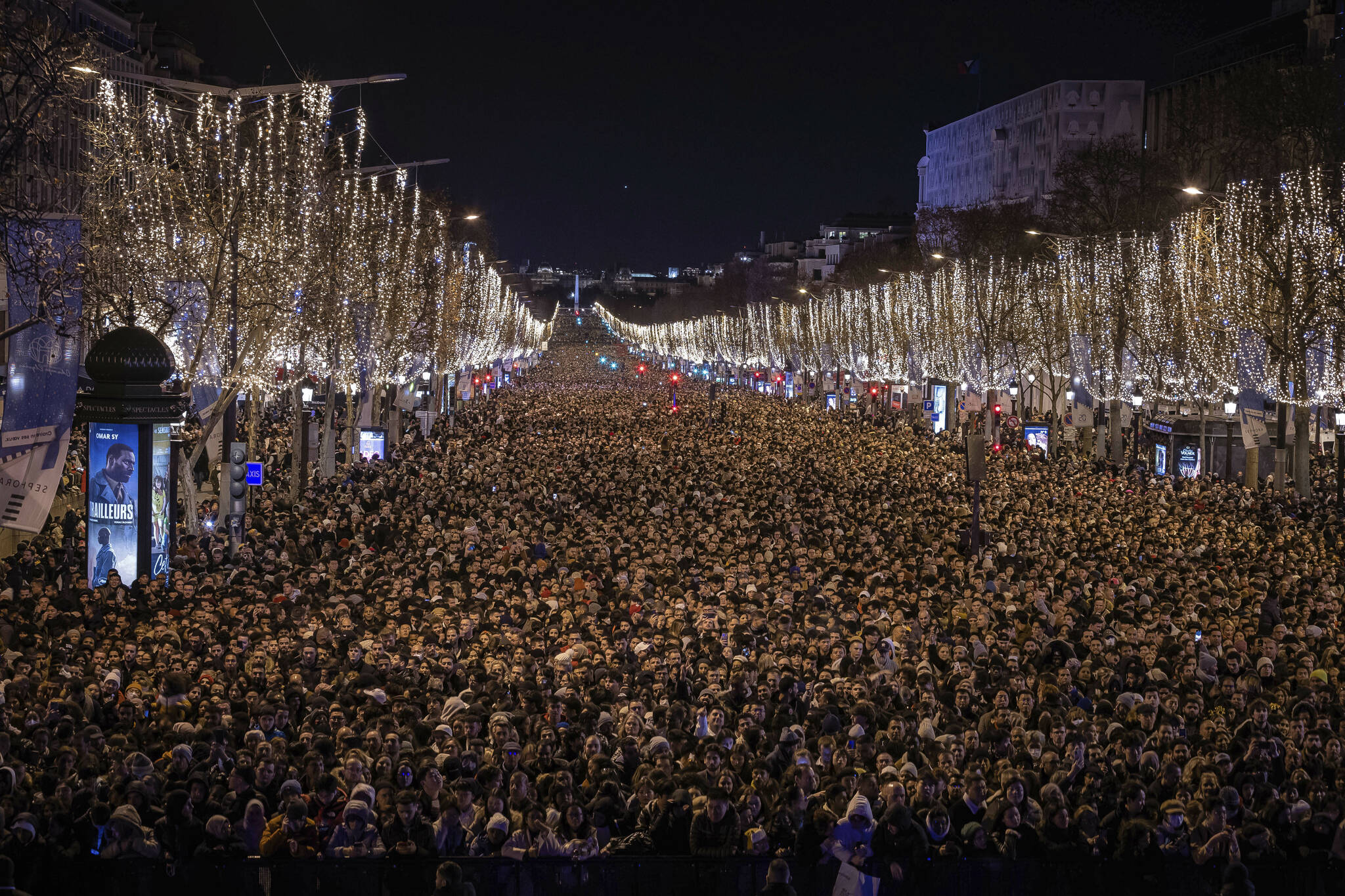 Revelers watch a sound and light show projected on the Arc de Triomphe as they celebrate the New Year on the Champs Elysees, in Paris, France, Saturday, Dec. 31, 2022. (AP Photo/Aurelien Morissard)
