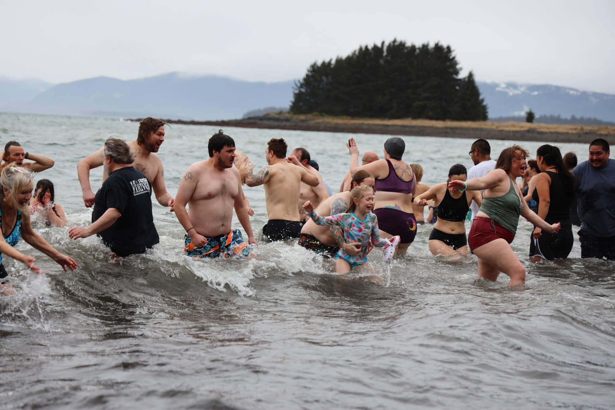 An array of emotions appear on the faces of people as they run in and out of the cold ocean water on a cloudy Sunday afternoon for the annual Polar Dip at the Auke Recreation Area.(Clarise Larson / Juneau Empire)