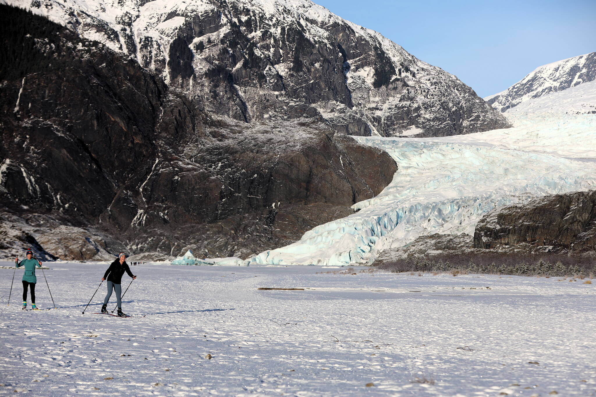 Skiers cross the frozen lake in front of the Mendenhall Glacier in December. A proposed expansion of the Mendenhall Glacier Recreational Area by the U.S. Forest Service envisions motorized tour boat access in most alternatives, but the three newest ones based on previous public feedback limit vessels to low-impact electronic access or none. (Clarise Larson / Juneau Empire)