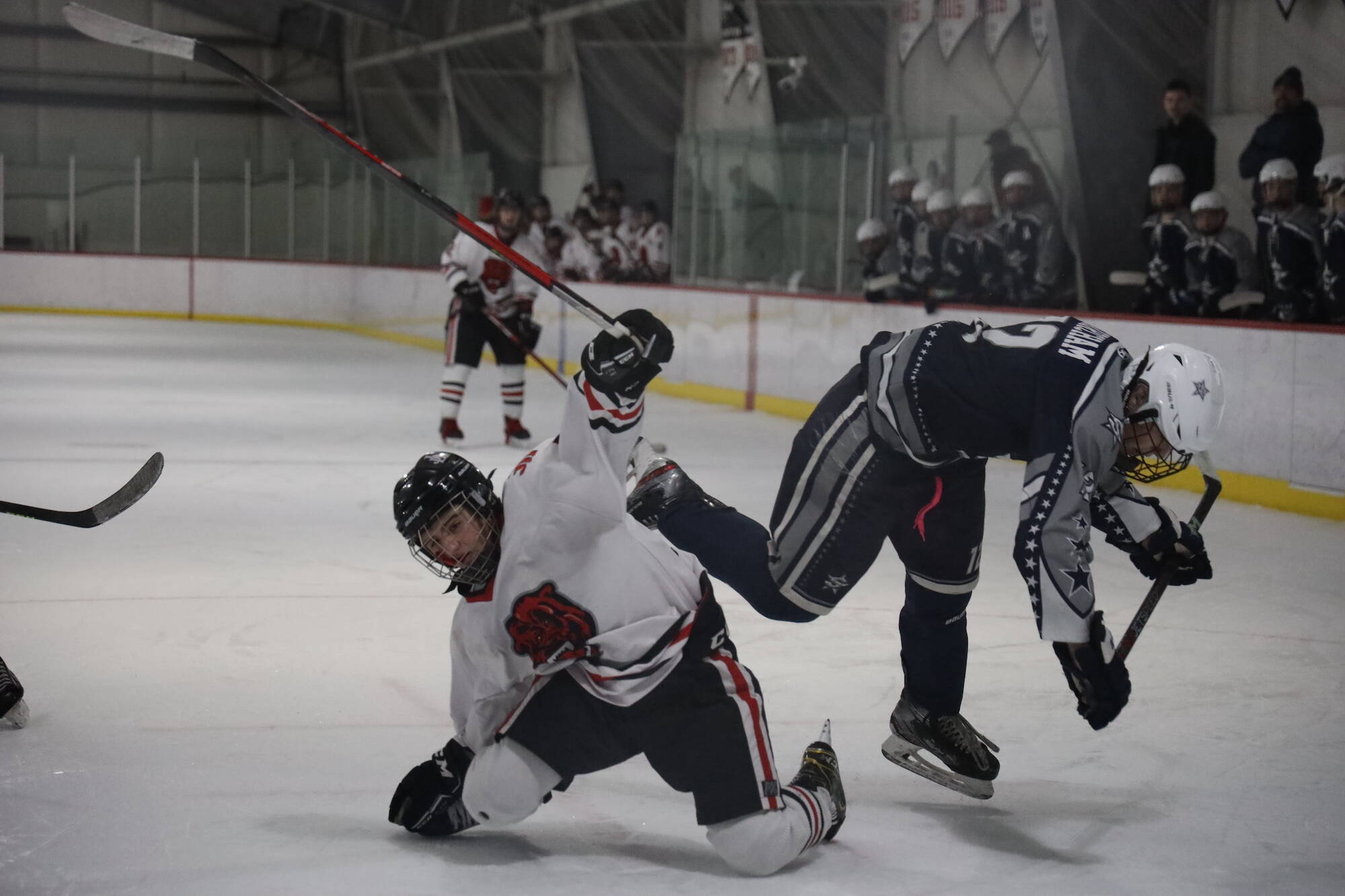 Players from the Juneau-Douglas High School: Yadaa.at Kalé Crimson Bears hockey team and the Soldotna High School Stars take tumble during the third period of their game Saturday afternoon. (Clarise Larson / Juneau Empire)