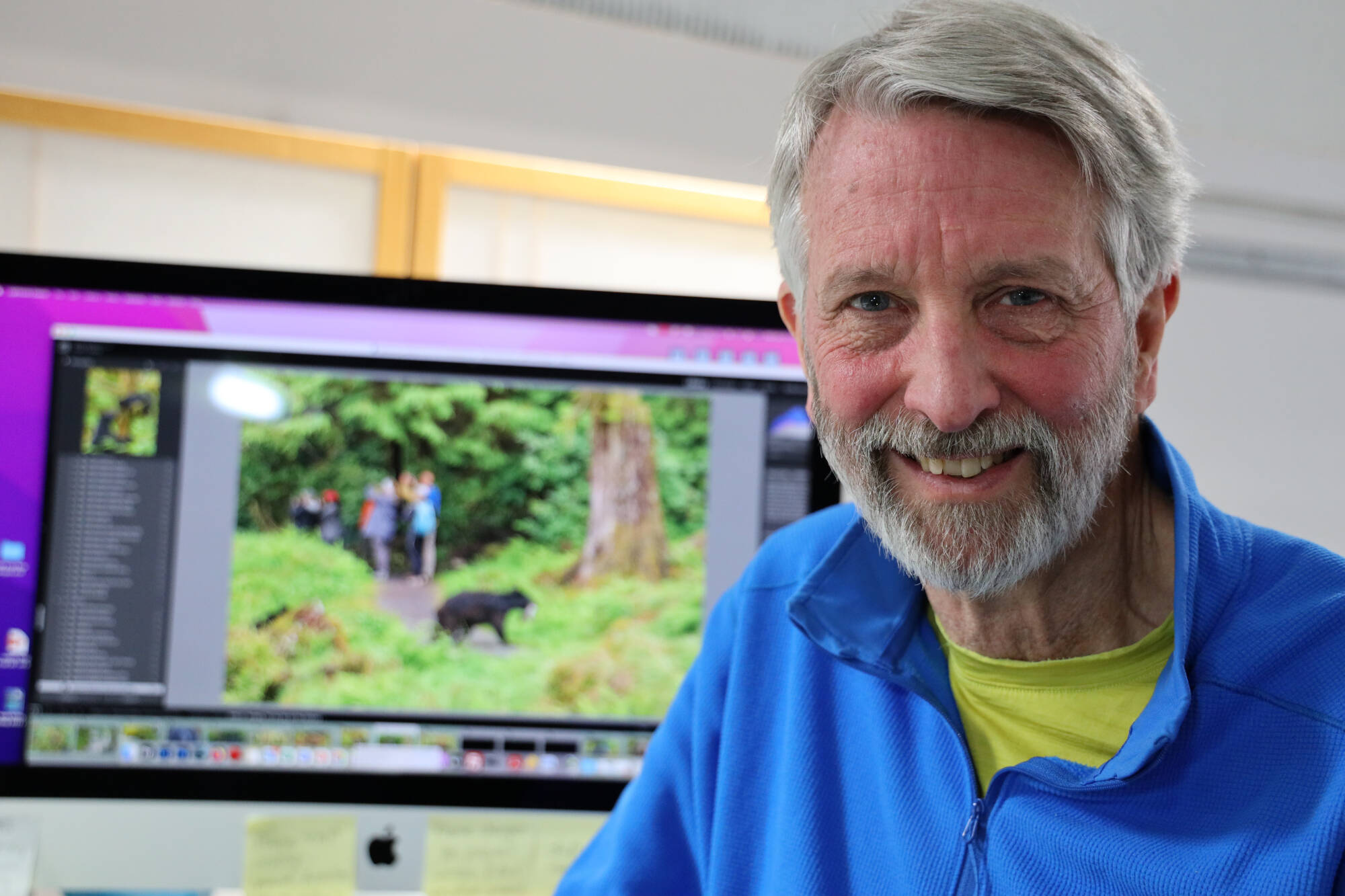 Juneau-based photographer Mark Kelley smiles next to a photo he took that was a part of his award-winning portfolio featured in the 2022 National Wildlife Magazine photo contest. The annual competition that receives more than 30,000 photos submitted by over 3,100 photographers with images coming in from across the globe. (Clarise Larson / Juneau Empire)