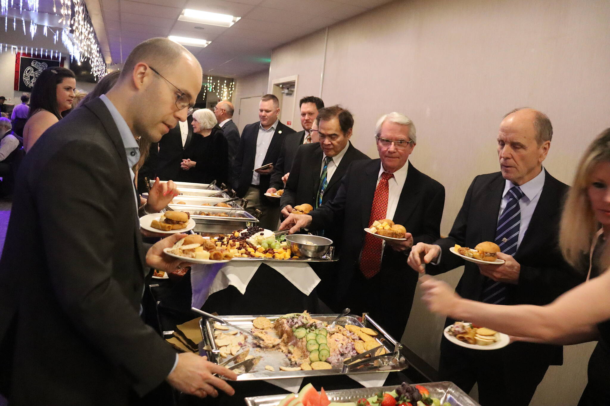Supporters of Gov. Mike Dunleavy, along with state lawmakers in both political parties, line up at the buffet at the inaugural celebration for the governor on Friday at Elizabeth Peratrovich Hall. (Mark Sabbatini / Juneau Empire)