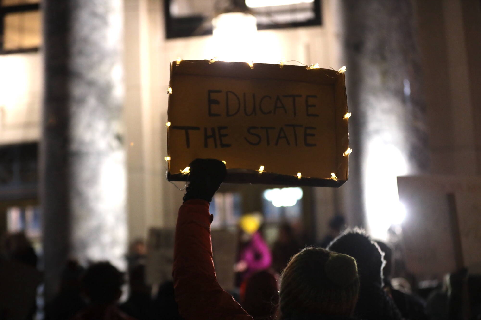 A protester holds a sign advocating for an increase in the state’s base student allocation during a rally at the steps of the Alaska State Capitol Monday evening. (Clarise Larson / Juneau Empire)