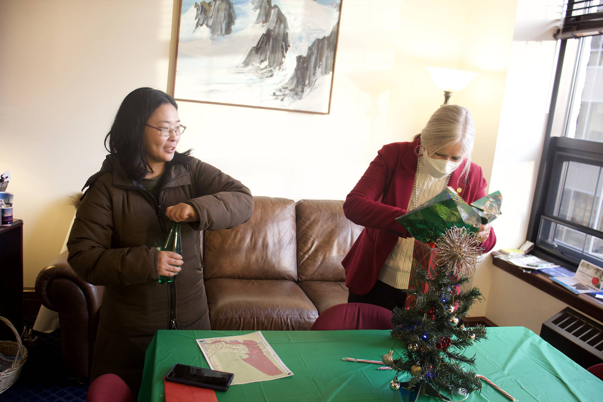 Katie Botz, left, gives state Rep. Andi Story of Juneau a present during an open house hosted by the local legislative delegation in December at the Alaska State Capitol. (Mark Sabbatini / Juneau Empire)