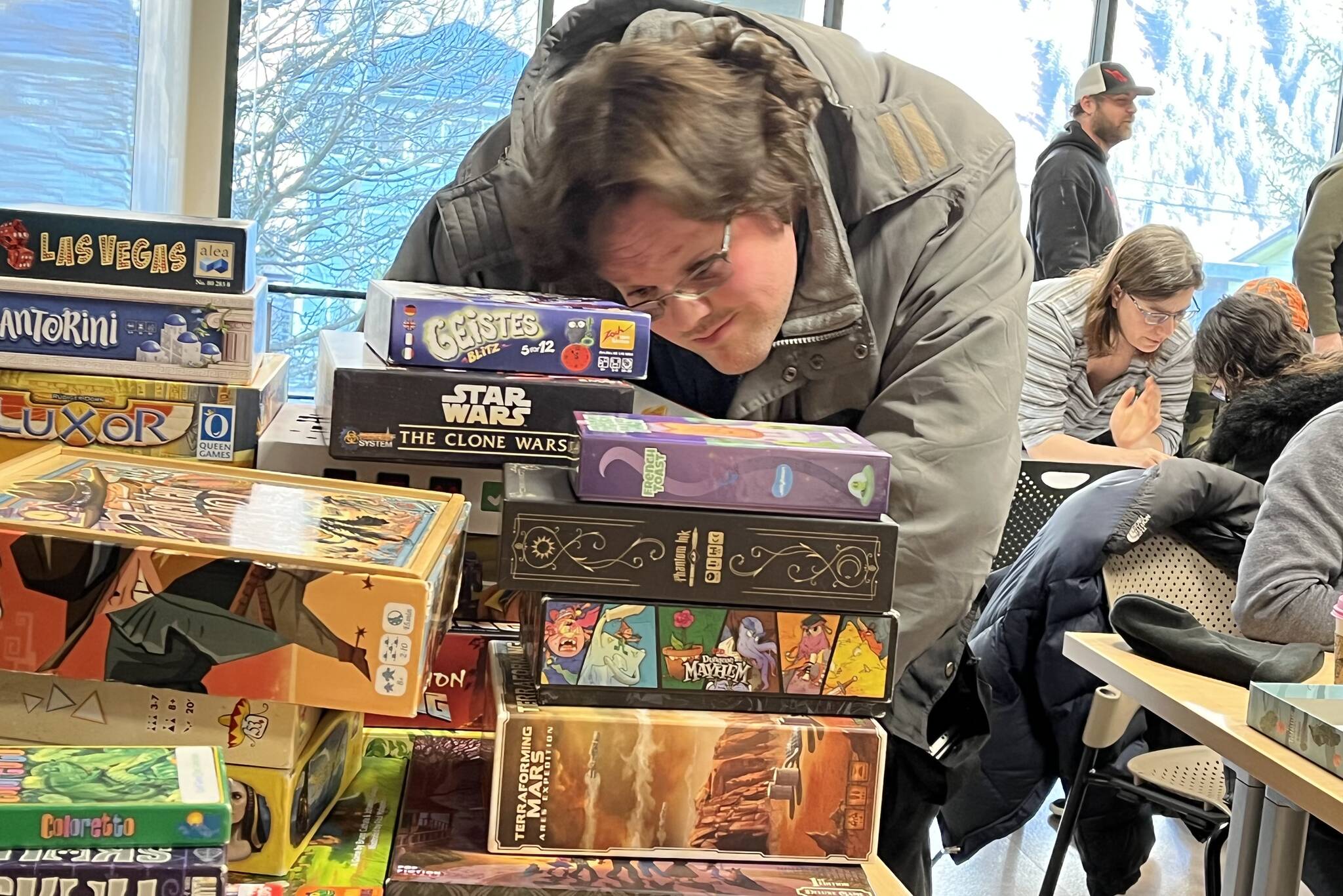 David Holmes digs through a pile of boardgames during Platypus Gaming’s two-day mini-con over the weekend at Douglas Public Library and Sunday at Mendenhall Public Library. (Jonson Kuhn / Juneau Empire)