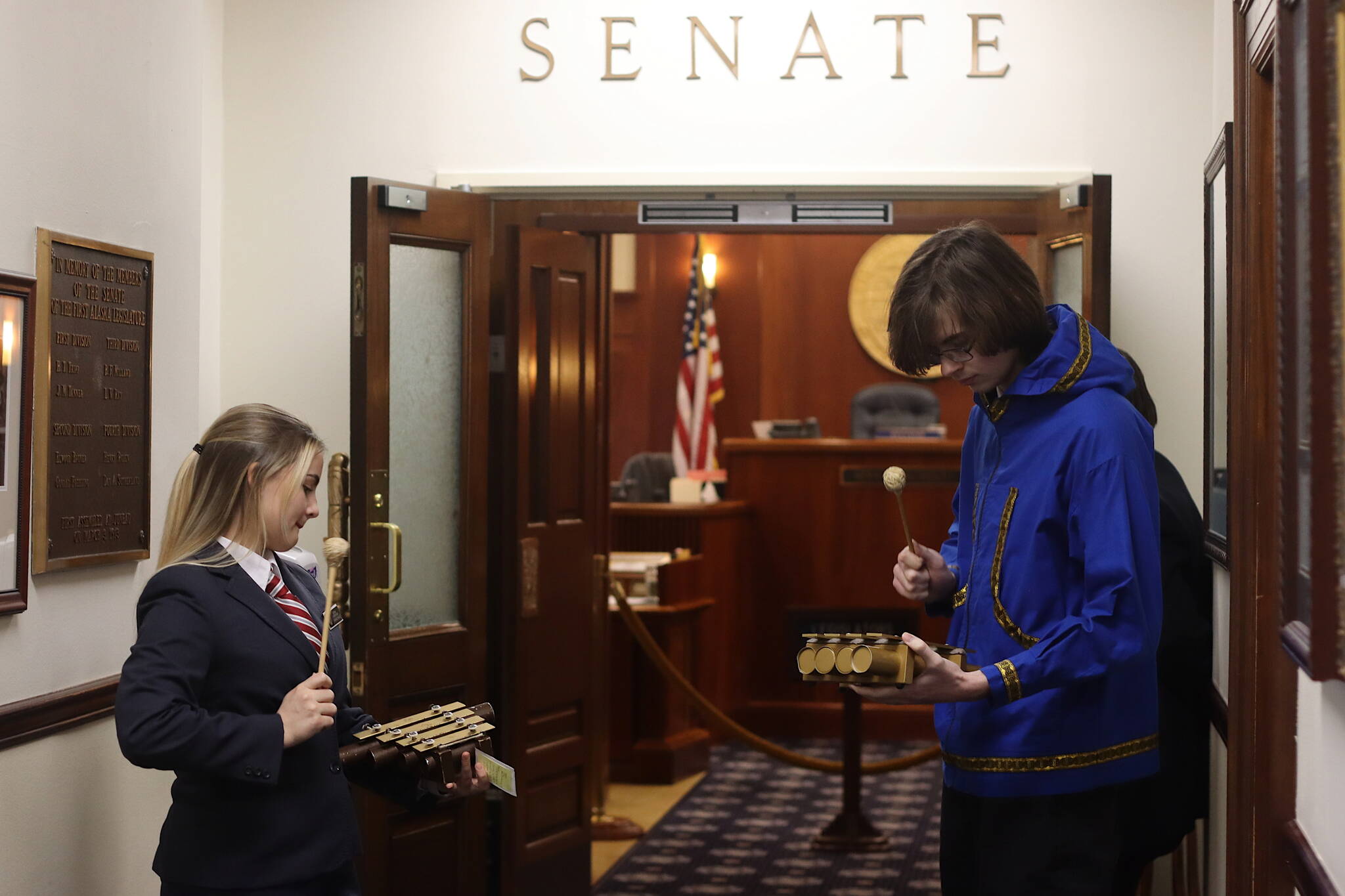 Senate pages Jenna Carpenter and Bernard Damerval play “Off To The Races” outside the Senate Chambers exactly 15 minutes before the start of the floor session. Pages then perform the tones alerting senators the session is about to start on all floors of the Capitol where the legislators have offices. The House relies on an electronic bell notification that plays the famous clock chime “Westminster Quarters.” (Mark Sabbatini / Juneau Empire)