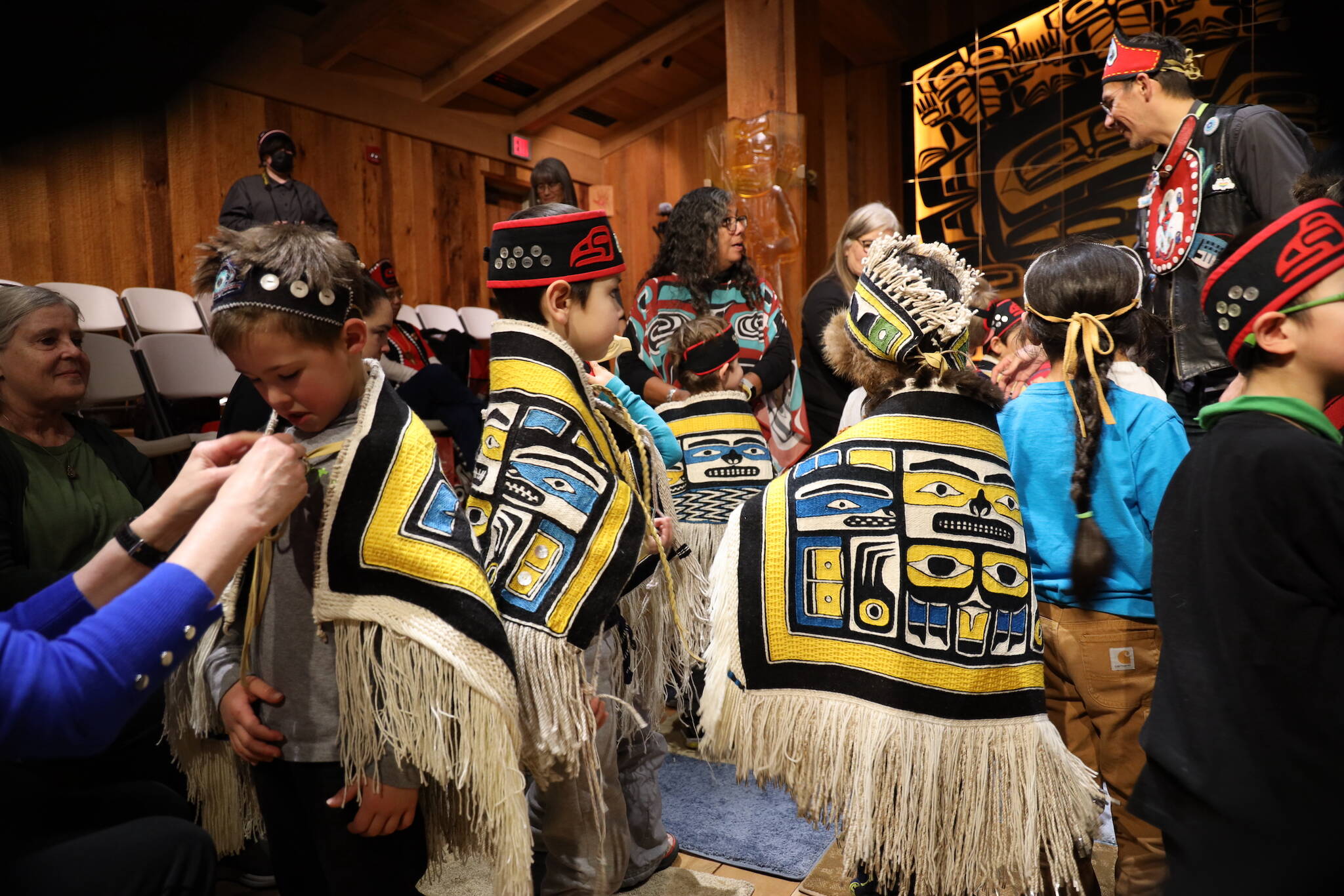 Clarise Larson / Juneau Empire 
Young students from the Tlingit Culture Language and Literacy program at Harborview Elementary School get help putting on Chilkat robes that were were weaved by student weavers who participated in a more than two-year-long apprenticeship to learn the craft.