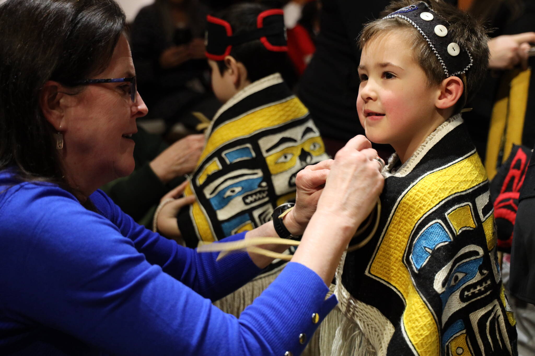 Clarise Larson / Juneau Empire
Myer Mallott from the Tlingit Culture Language and Literacy program at Harborview Elementary School smiles Wednesday afternoon as Joanne Seyl, one of the student weavers, helps put on his robe she weaved.