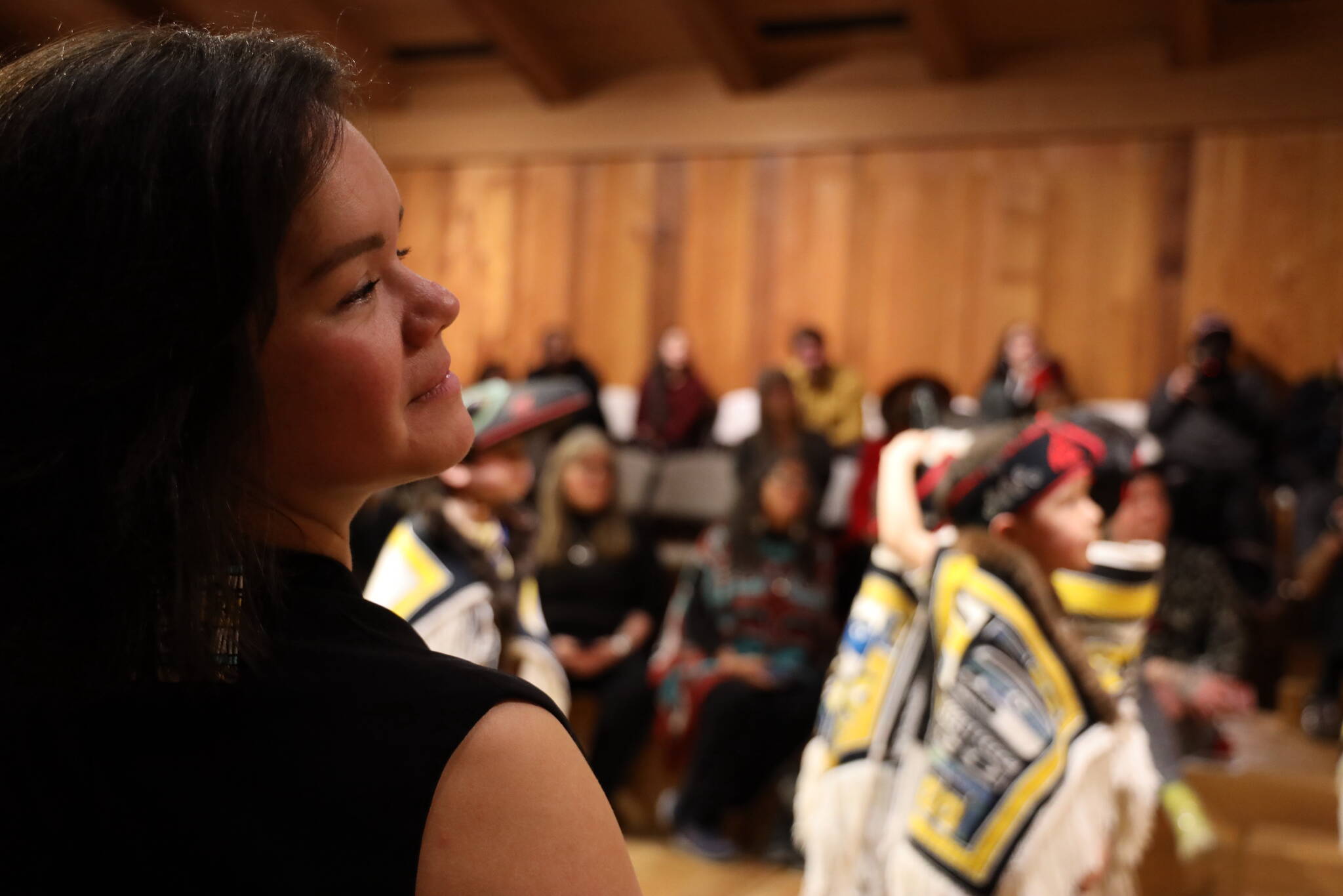 Lily Wooshkindein Da.áat Hope, a multiple-medium Juneau-based artist who taught the craft of Chilkat weaving to dozens of student weavers over the past two years, smiles while watching students from the Tlingit Culture Language and Literacy program at Harborview Elementary School perform a dancing-of-the-robes ceremony Wednesday afternoon. (Clarise Larson / Juneau Empire)