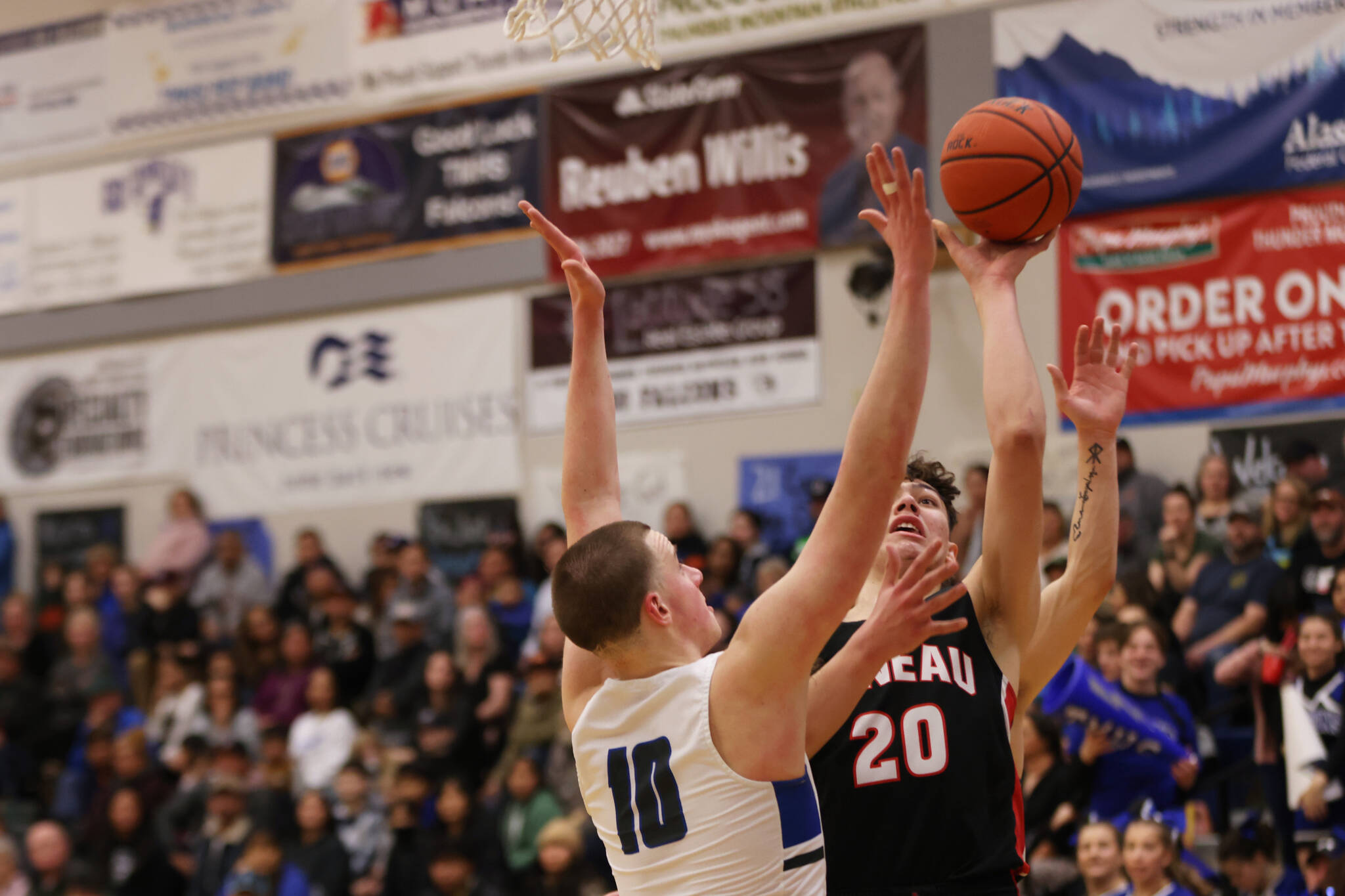 JDHS senior Orion Dybdahl (20) shoots over the outstretched arms of TMHS junior James Polasky early in a Crimson Bears comeback win at Thunder Mountain High School. (Ben Hohenstatt / Juneau Empire)