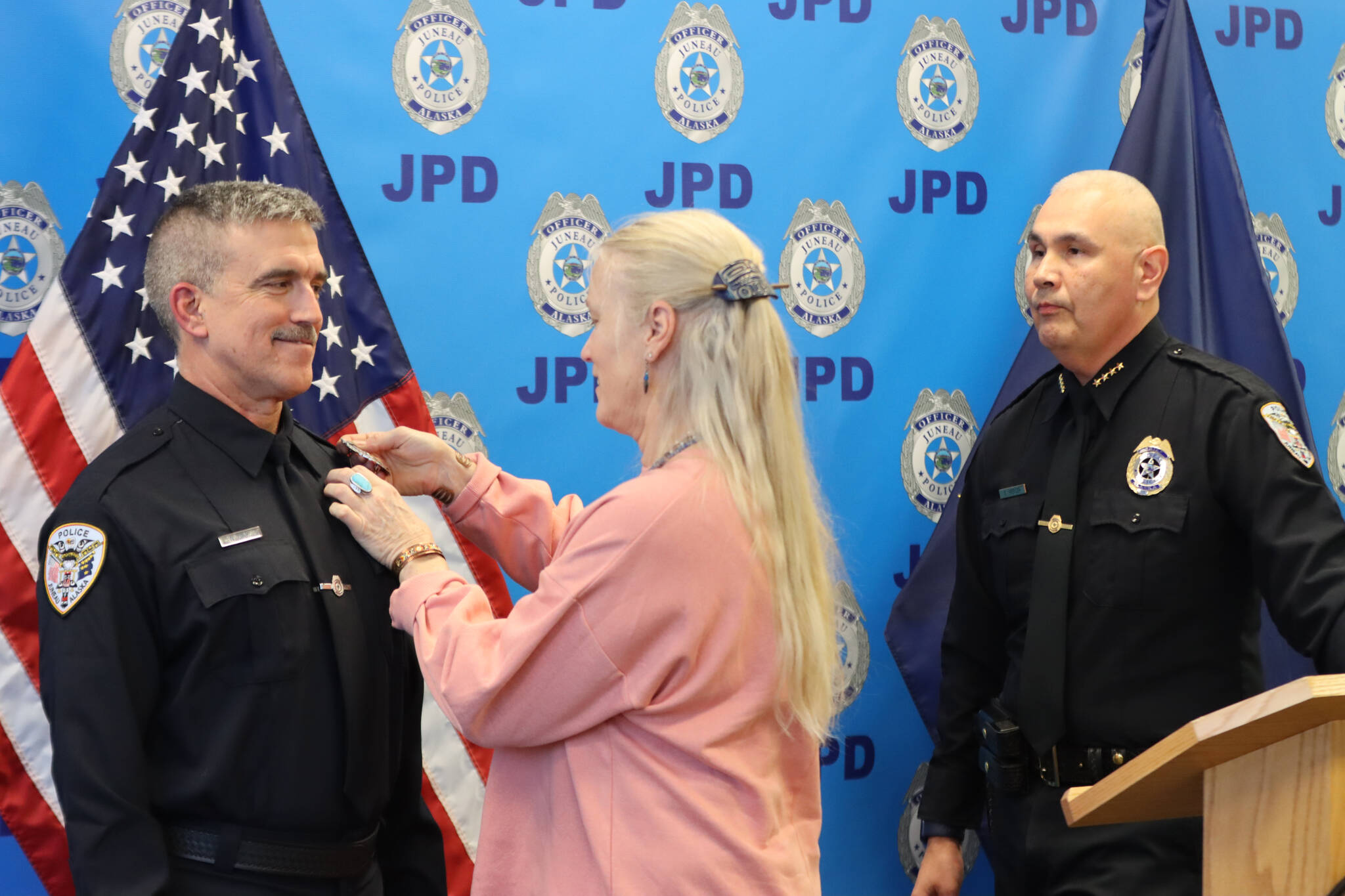 Officer William Hicks stands as his wife Corey Hicks pins a new officer’s badge to his uniform during a swearing in ceremony for Hicks on Thursday. (Jonson Kuhn / Juneau Empire)