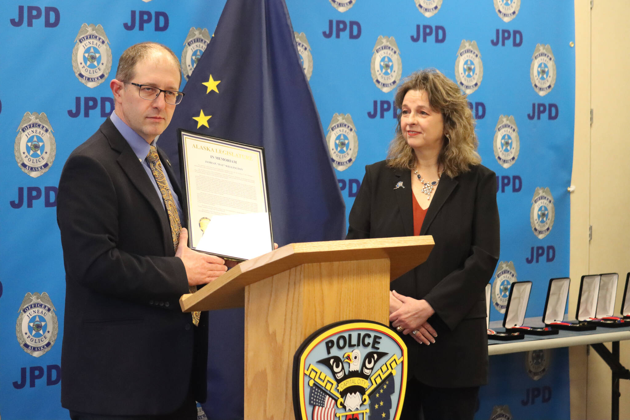 State Senator Jesse Kiehl presents legislative memoriam to Karen Bonnett Petersen who accepted the award during JPD’s award ceremony on Monday on behalf of her uncle, late JPD Chief Pat Wellington, who passed away in May 2021. (Jonson Kuhn /Juneau Empire)