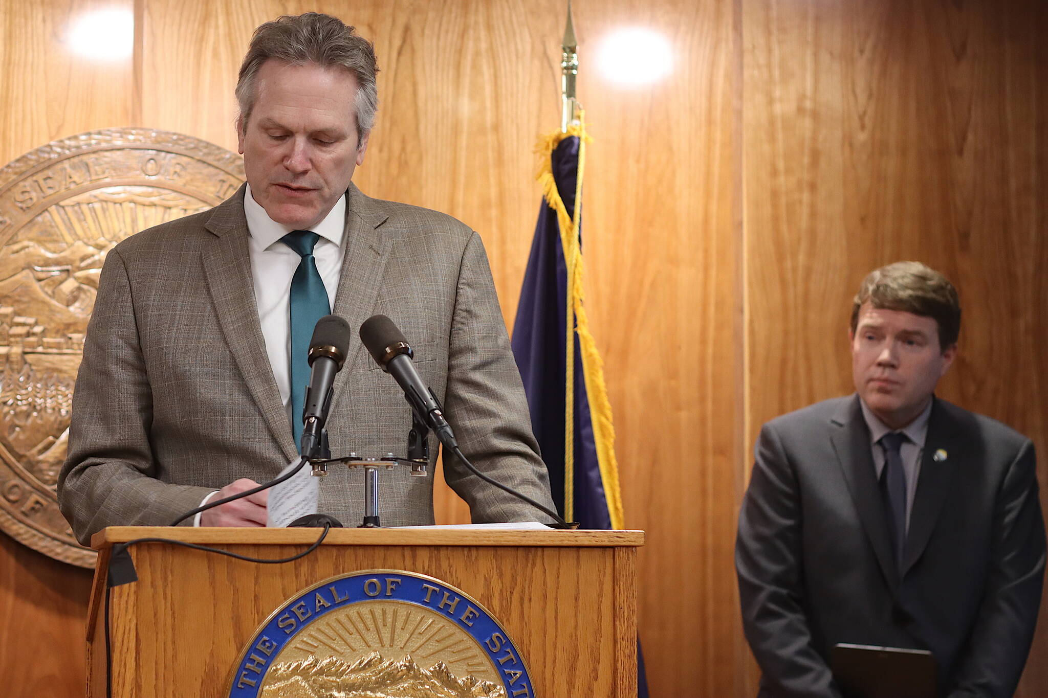 Gov. Mike Dunleavy, left, reads highlights from his revised state budget proposal for the 2024 fiscal year as Department of Transportation and Public Facilities Commissioner Ryan Anderson waits to present revisions within his department. Among the most significant revisions are required matching funds for federal allocations to the Alaska Marine Highway system. (Mark Sabbatini / Juneau Empire)