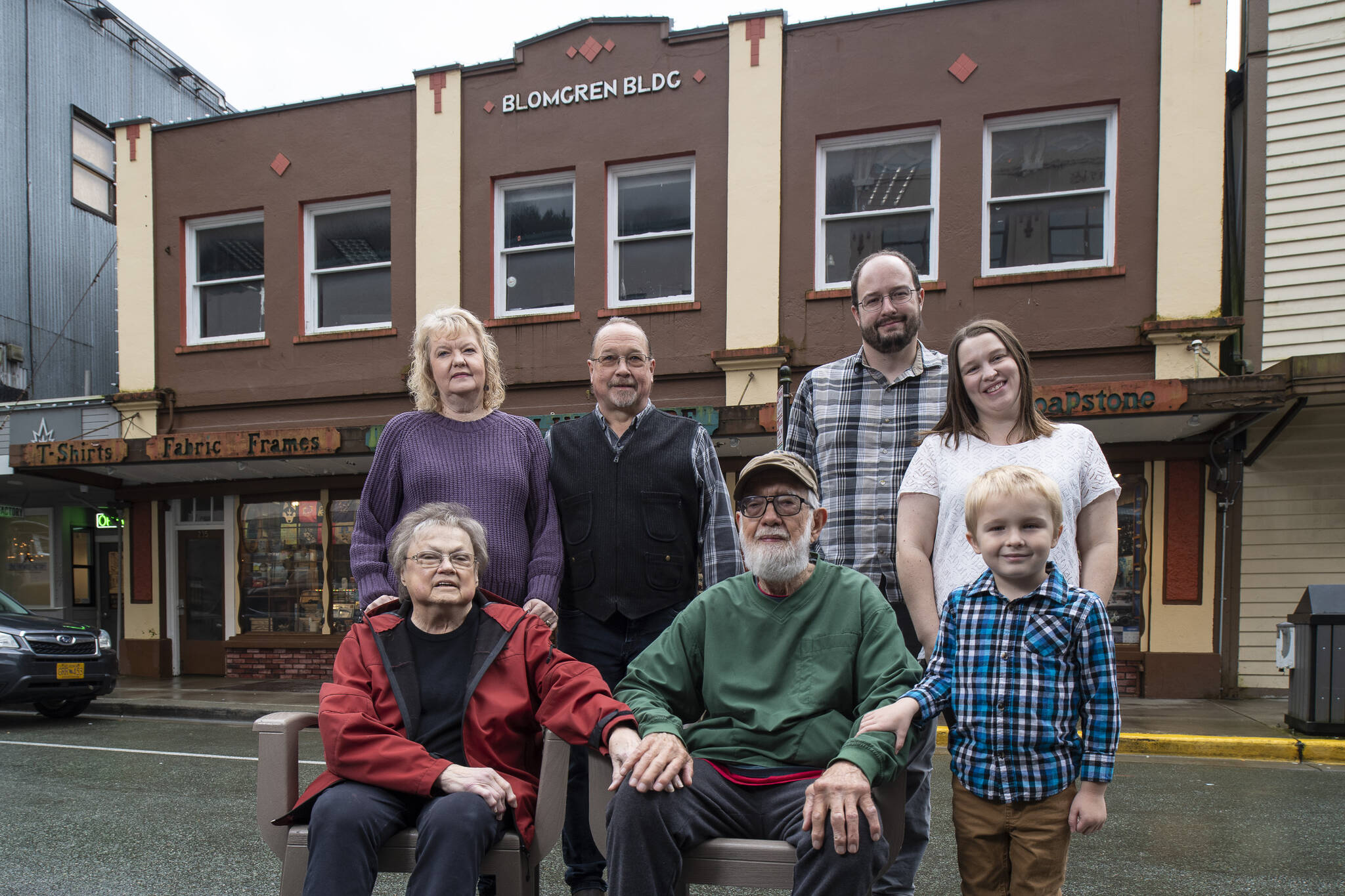 Four generations of the Wiley family pose before the Front Street business the family has owned for fifty years in the historic Blomgren Building. Sally and Fred Wiley, seated, took over the Ben Franklin Store in 1972. Shannon and Mike Wiley stand with Stephen Bishop and Meagan Wiley Bishop and young Nolan Bishop. Today Mike and his daughter Meagan operate the store together. (Michael Penn / For Downtown Business Association)
