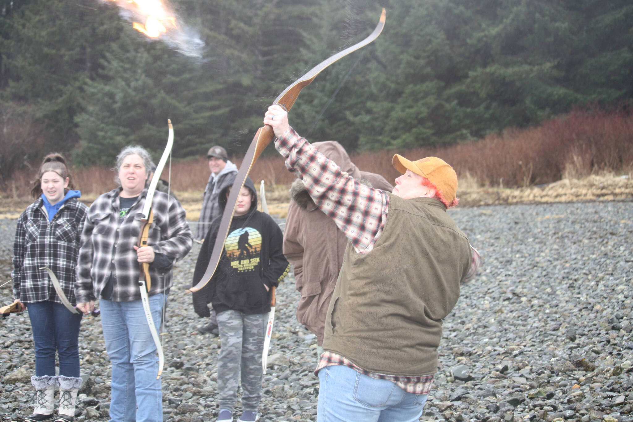 Tiffany Sargent Hallquist shoots a flaming arrow into the air to honor her late father Daniel Sargent during a memorial ceremony on Saturday at Auke Bay Recreation Area. (Jonson Kuhn / Juneau Empire)