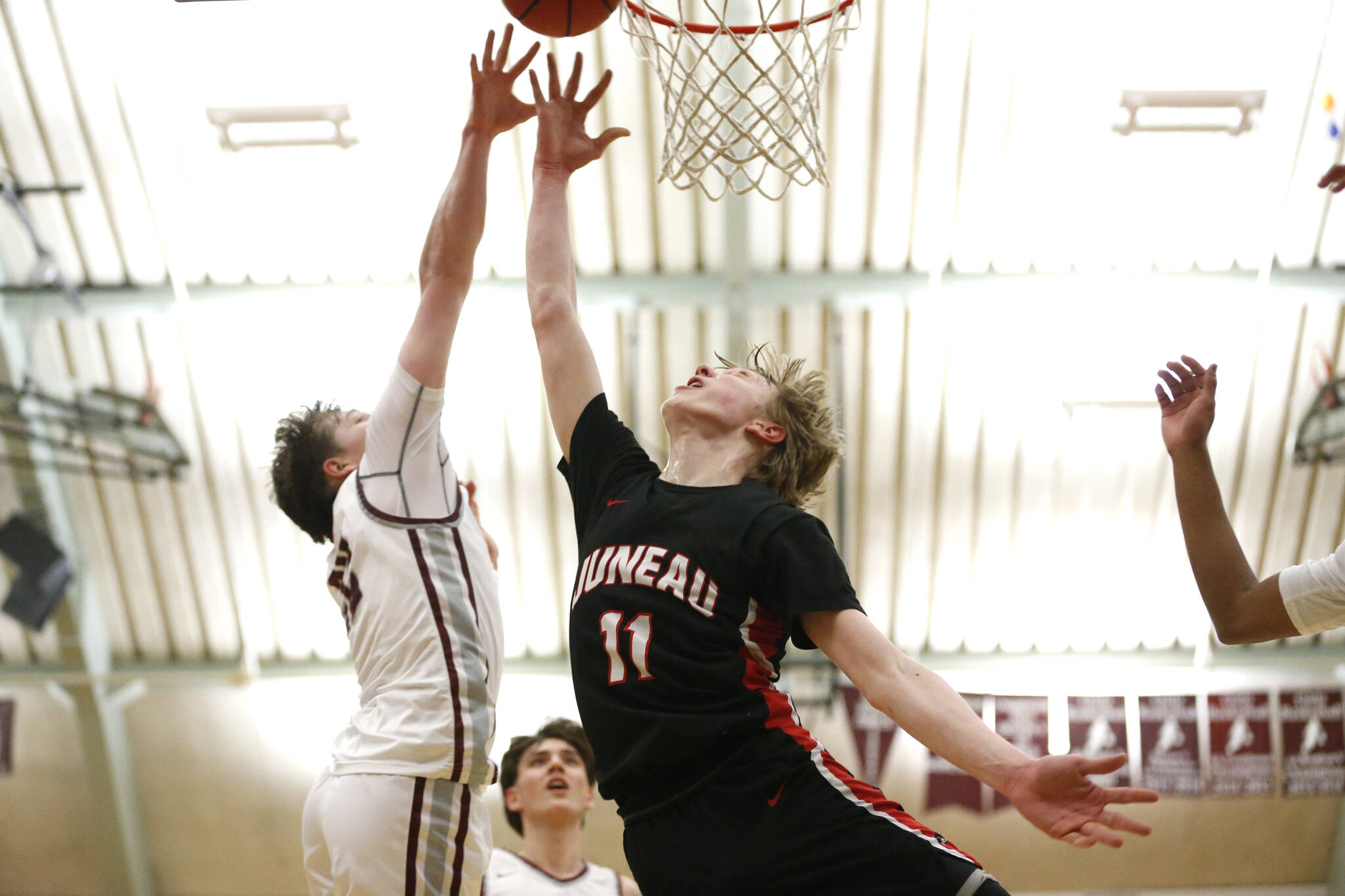 Kayhi’s Archie Dundas (22) attempts to block Juneau’s Sean Oliver (11) during Juneau’s 71-52 loss to Kayhi on Friday at the Clarke Cochrane Gymnasium. (Christopher Mullen / Ketchikan Daily News)