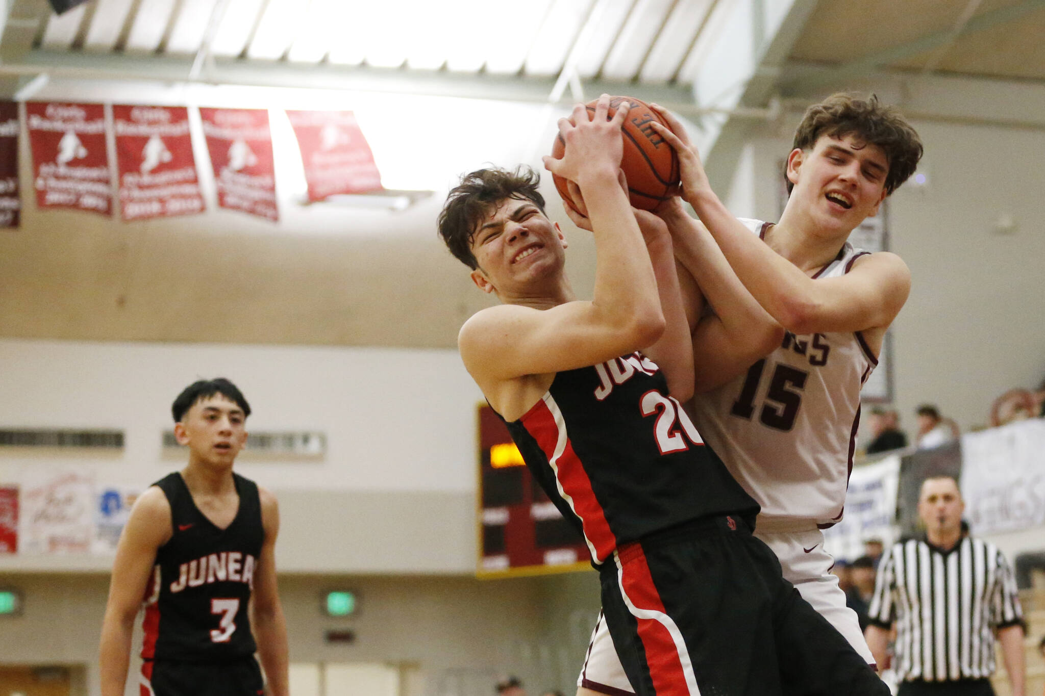Juneau’s Orion Dybdahl (20) forces a jump ball with Kayhi’s Jared Rhoads (15) during Juneau’s 71-52 loss to Kayhi on Friday at the Clarke Cochrane Gymnasium. (Christopher Mullen / Ketchikan Daily News)