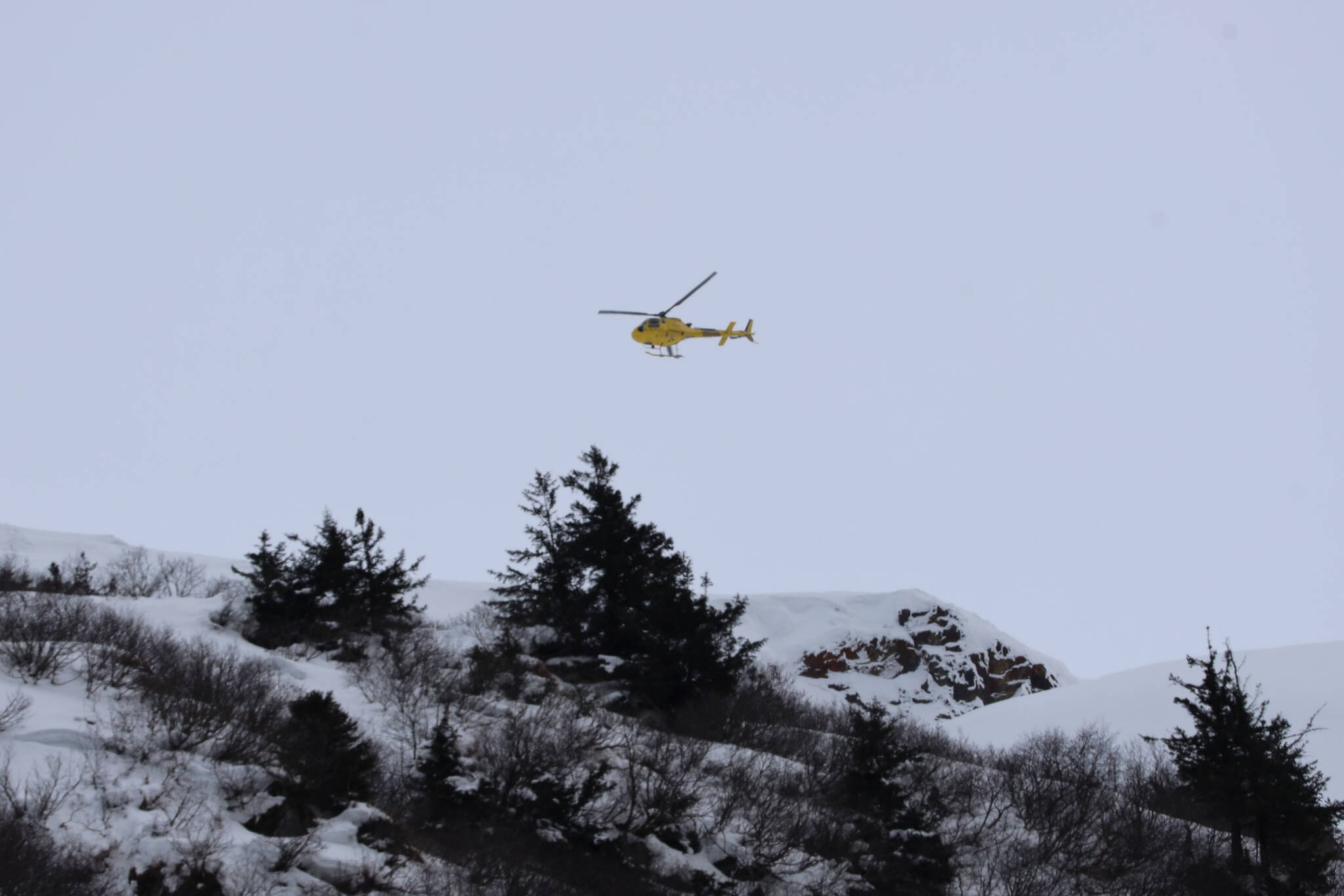The Alaska Department of Transportation and Public Facilities drops explosives via helicopter to trigger controlled avalanches above Thane Road Tuesday afternoon. (Clarise Larson / Juneau Empire)