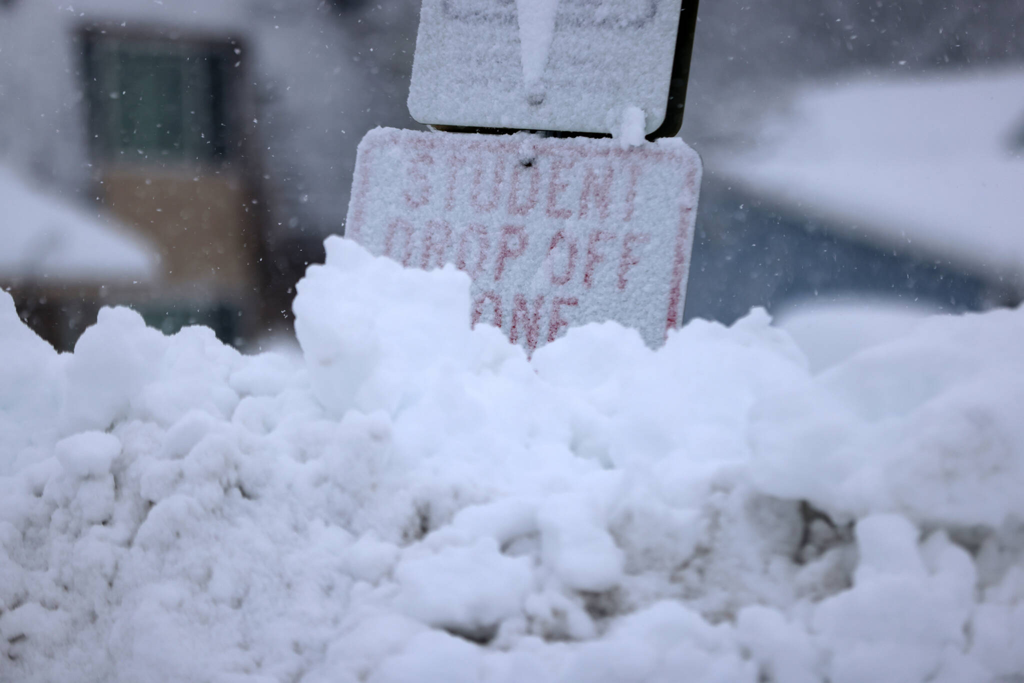 Ben Hohenstatt / Juneau Empire 
A snow berm reaches the letters on a “Student Drop Off Zone” sign.