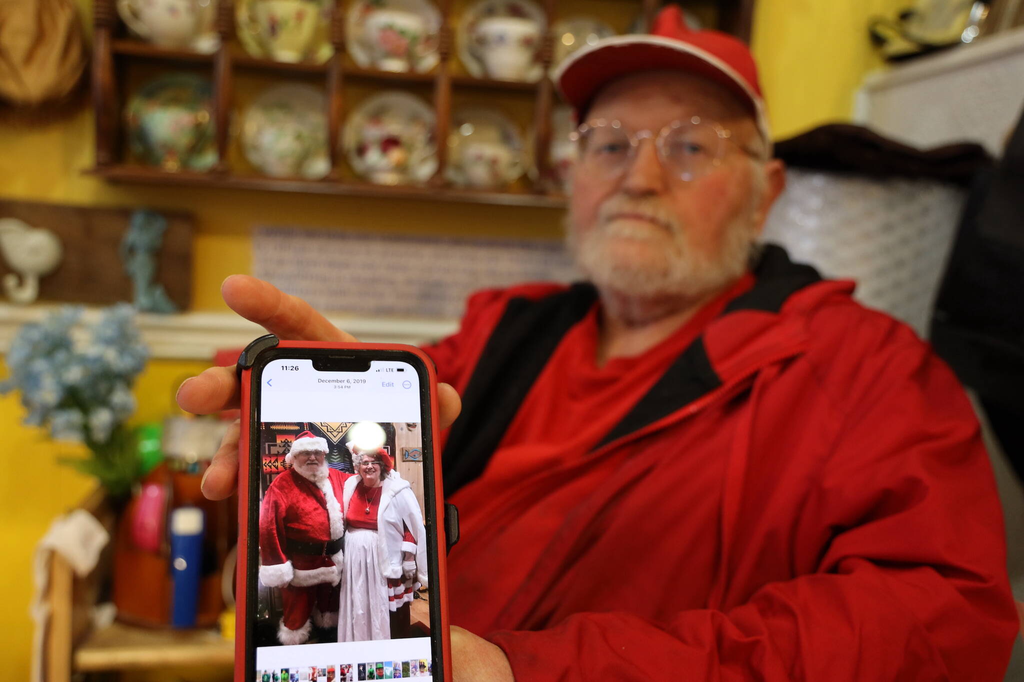 Dale Hudson holds his phone showing a photo of him and his late wife, Suzanne, dressed up as Mr. and Mrs. Claus. Dale is in the process of liquidating his wife’s store, Nana’s Attic, after her recent death in late February. (Clarise Larson / Juneau Empire)