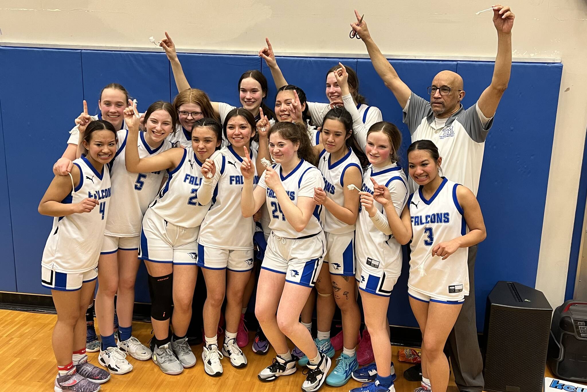 TMHS coach Andy lee poses with the Thunder Mountain Lady Falcons, the new region champions on Friday, after defeating JDHS in the final match up of the tournament. (Jonson Kuhn / Juneau Empire)