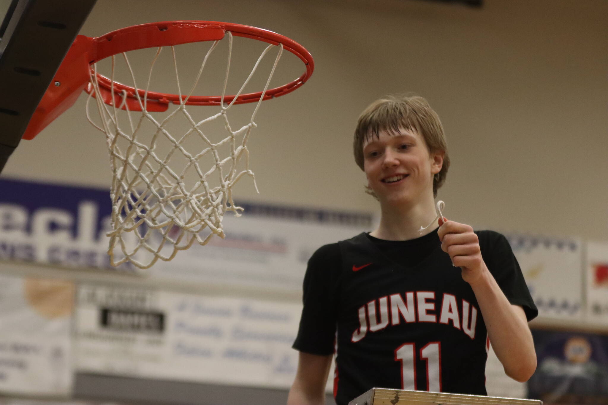 JDHS junior Sean Oliver (11) holds string from the championship net after a win against Ketchikan High School, making the Crimson Bears this year’s Region V 4A Tournament champs. Oliver finished the game with 30 points, six 3-pointers and a fourth-quarter slam dunk. (Jonson Kuhn / Juneau Empire)