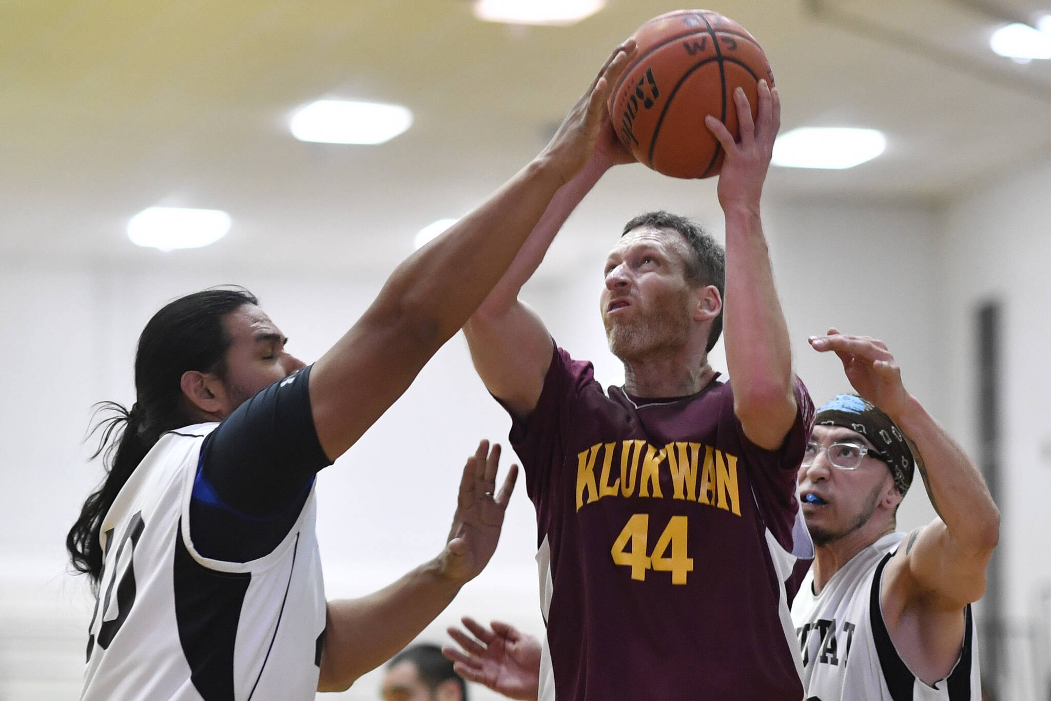 Klukwan’s Andrew Friske, center, shoots against Yakutat’s Derek James, left, at the Juneau Lions Club 73rd Annual Gold Medal Basketball Tournament at Juneau-Douglas High School: Yadaa.at Kalé on Tuesday, March 19, 2019. This year’s tournament starts on Sunday, March 19-25 at JDHS. (Michael Penn | Juneau Empire File)