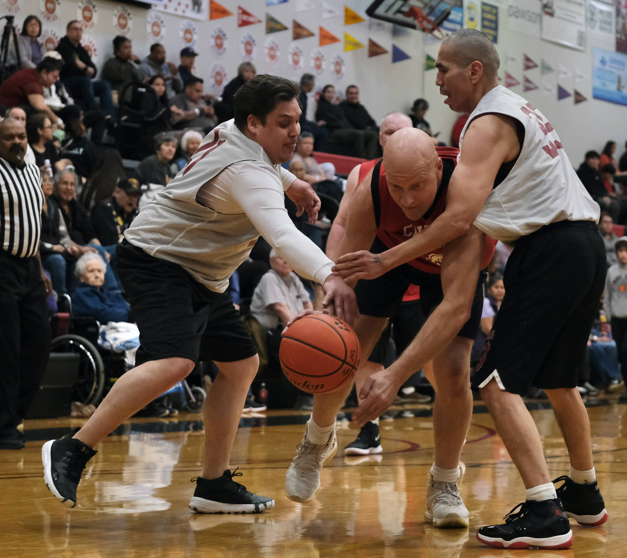 Hoonah’s Adam Lee (21) and Louie White Jr. (35) strip a ball from Klukwan’s Jeff Sharnbroich during Masters Bracket action in the Gold Medal Basketball Tournament, Monday, March 20, at Juneau-Douglas High School: Yadaa.at Kalé. (Klas Stolpe/For the Juneau Empire)