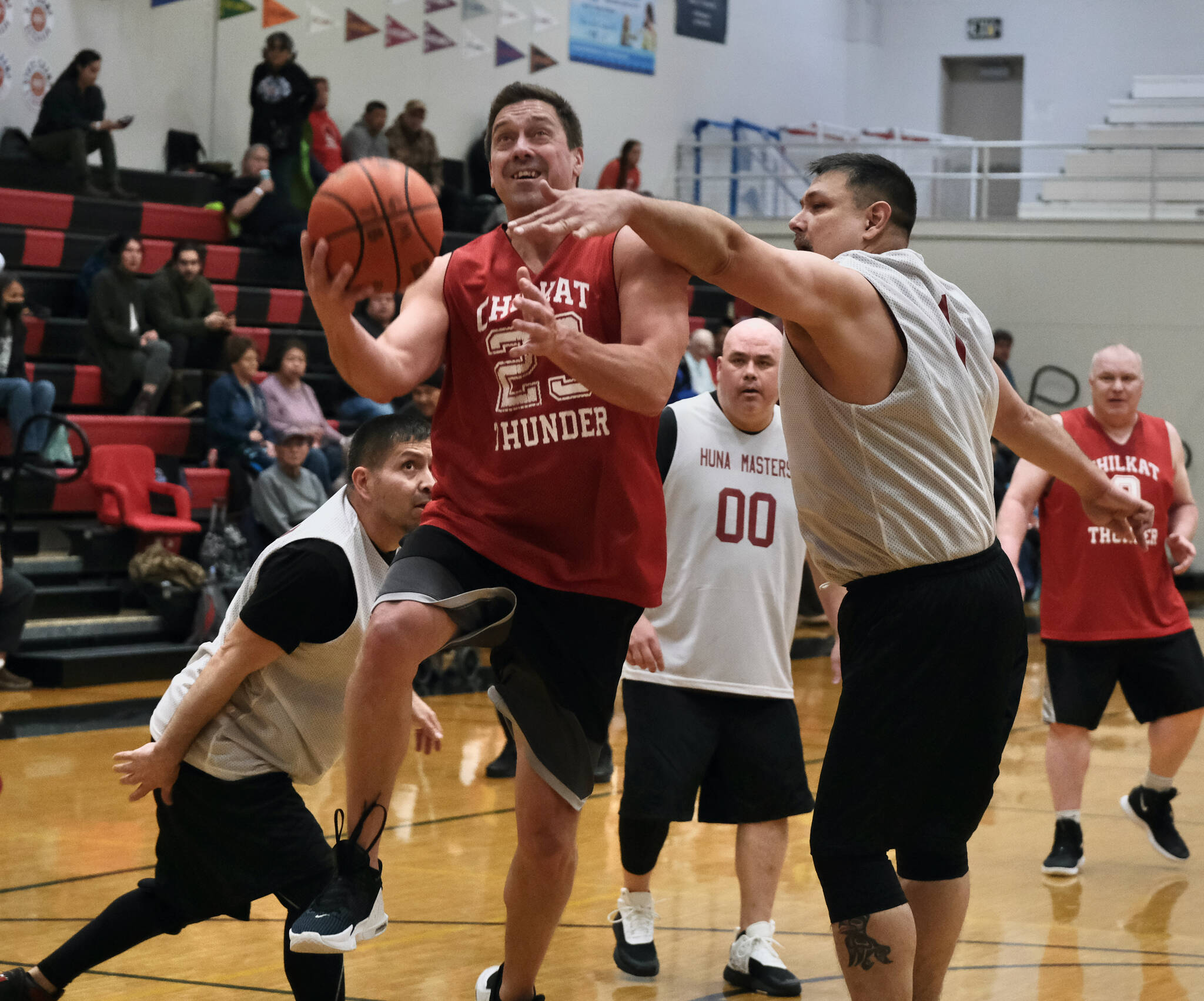 Klukwan's Russ Stevens (23) scores against Hoonah's Michael Mills (1) during Masters Bracket action in the Gold Medal Basketball Tournament, Monday, March 20, at Juneau-Douglas High School: Yadaa.at Kalé. (Klas Stolpe/For the Juneau Empire)