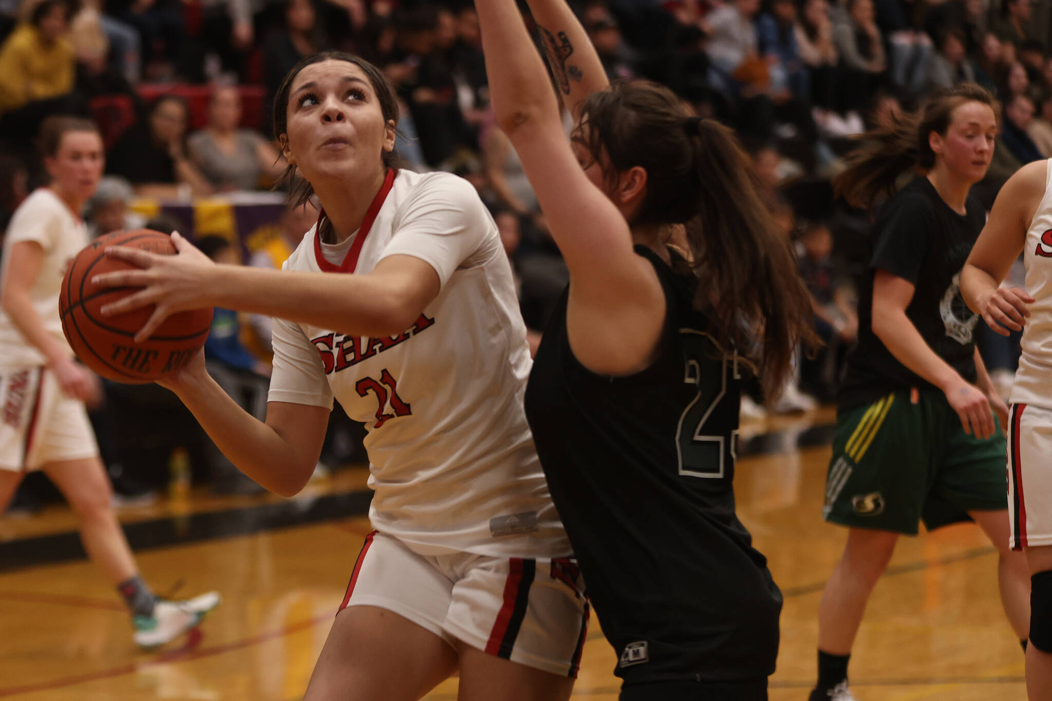 Hoonah’s Mackenzie Nichols (21) eyes the hoop while defended by Prince of Wales’ Michaela Demmert in the first half of a 63-43 Prince of Wales win. (Ben Hohenstatt / Juneau Empire)