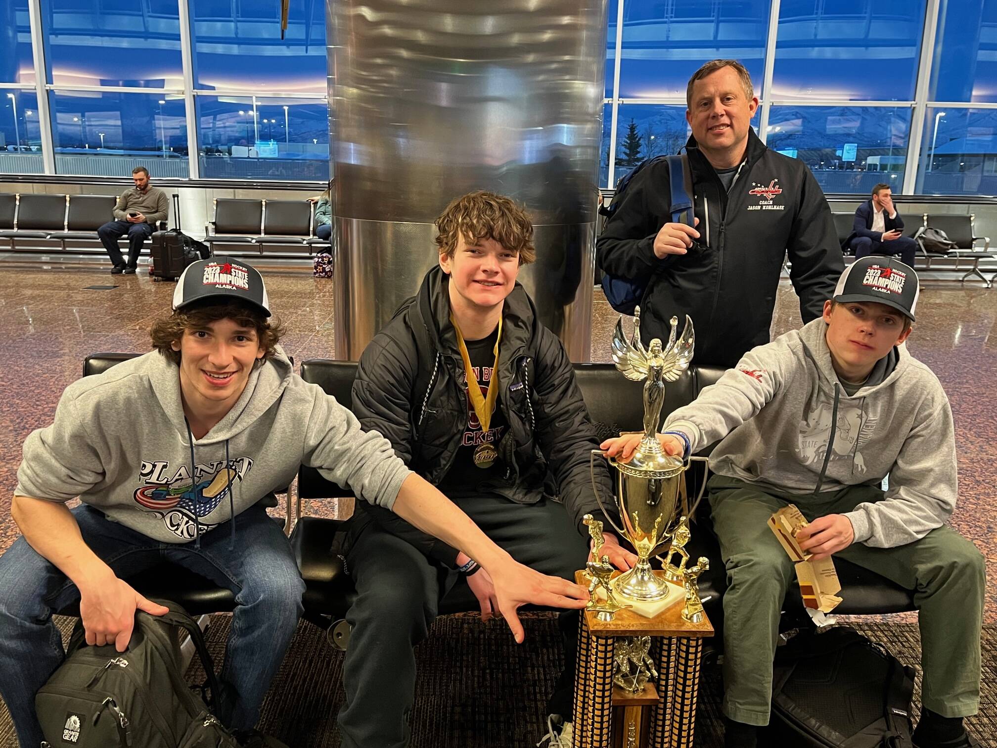 Coach Jason Kohlhase joins players, from left, Lake Bartlett, Brandon Campbell and son, Karter Kohlhase, around the team's 18-and-Under, Tier A hockey state championship trophy. Campbell ended the triple overtime marathon by ramming home a rebound off teammate Kohlhase's face off shot.
 (Courtesy Photo / Kristin Bartlett)