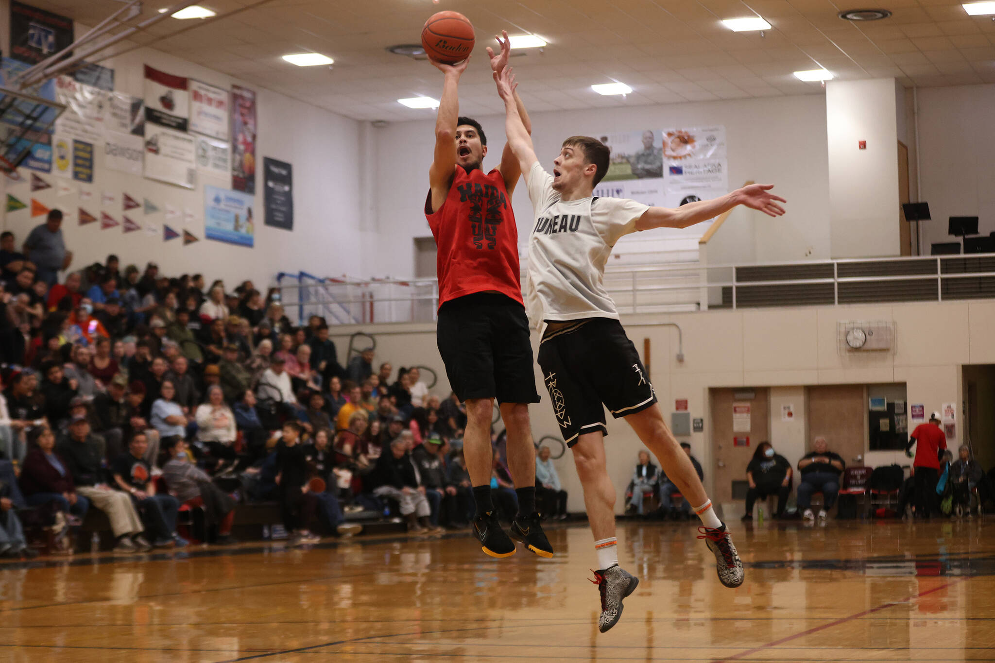 Hydaburg’s Darren Edenshaw shoots from deep while Juneau’s Kaleb Tompkins attempts to disrupt the shot. Edenshaw finished with a game-high 24 points, but Juneau left with an 86-70 victory and a B Bracket championship game berth. (Ben Hohenstatt / Juneau Empire)
