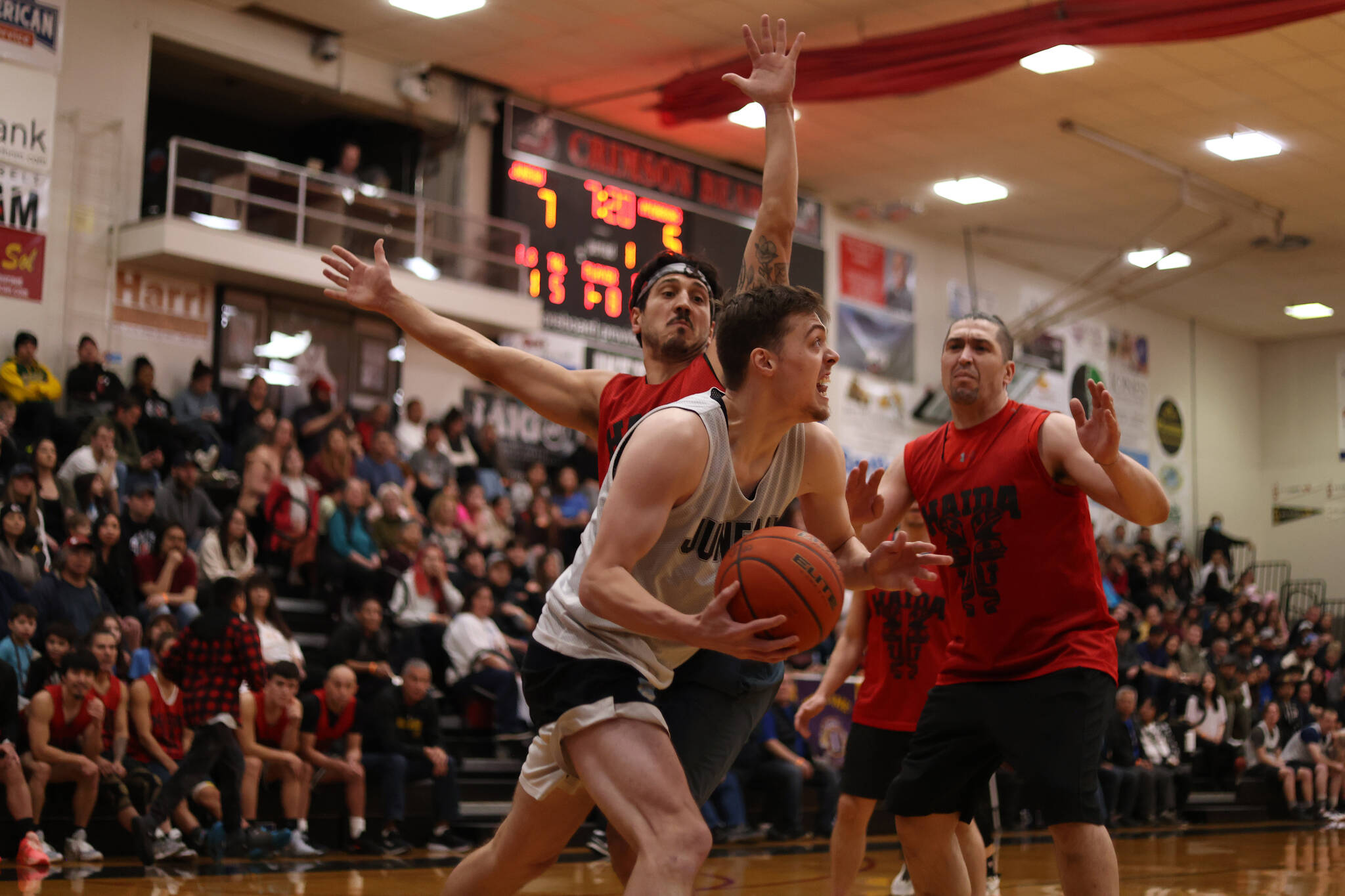 Juneau’s Kaleb Tompkins drives toward the basket while defended by Hydaburg’s Claude Young and George Peratrovich in the first quarter of Juneau’s eventual Juneau Lions Club 74th Gold Medal Tournament B Bracket championship. Tompkins took home B Bracket MVP honors following the Saturday night game. (Ben Hohenstatt / Juneau Empire)