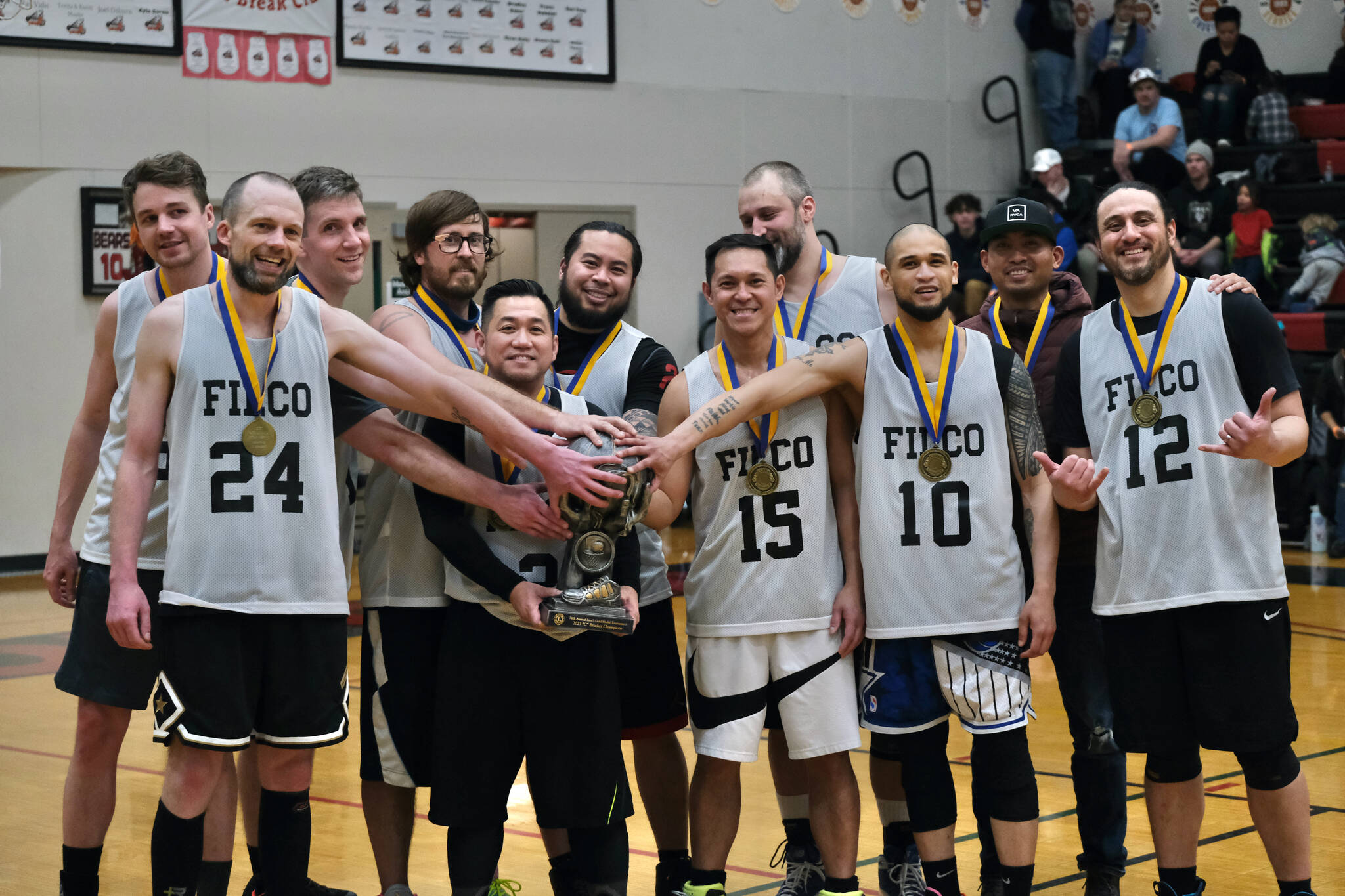 C Bracket champions Filcom pose with their trophy. (left to right) Charlie Herrington, Alex Heumann, Tom Gizler, Adam Brown, Mike Lim, Andrew Malacas, Nino Bohulano, Ray Zimmer, Larry Cooper, Ronin Tagsip and Jason Haskell at the Gold Medal Basketball Tournament, Saturday, March 25, at Juneau-Douglas High School: Yadaa.at Kalé. (Klas Stolpe/For the Juneau Empire)